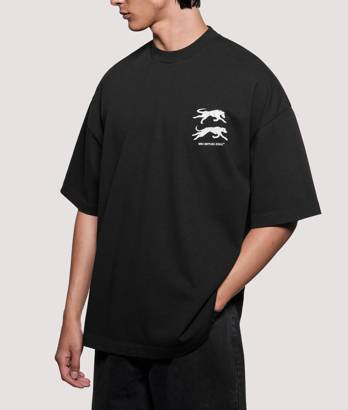 MKI MIYUKI ZOKU Oversized Box Fit Greyhound T-Shirt in Black at EQVVS Menswear. Angled model front shot.