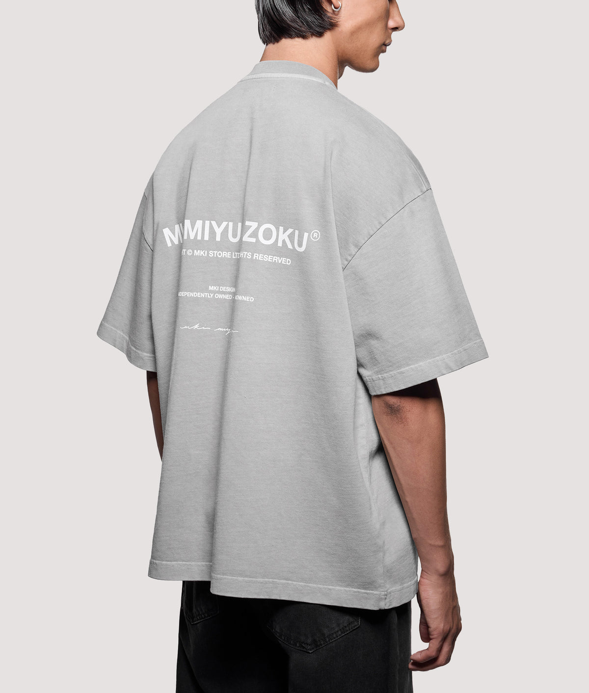 MKI MIYUKI ZOKU Oversized Box Fit Design Studio T-Shirt in Pigment Stone at EQVVS Menswear. Angled model back shot.