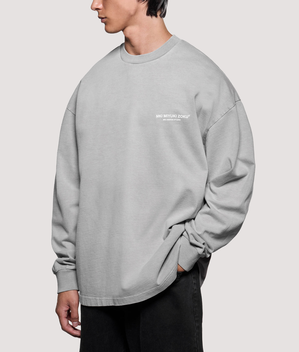 MKI MIYUKI ZOKU Oversized Box Fit Design Studio Long Sleeve T-Shirt in Pigment Stone at EQVVS Menswear. Angled model front shot.