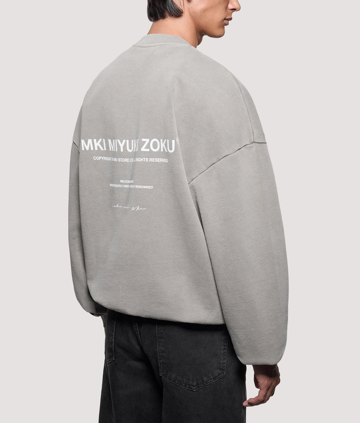 MKI MIYUKI ZOKU Oversized Box Fit Design Studio Crewneck Sweatshirt in Pigment Stone at EQVVS Menswear. Angled model back shot.