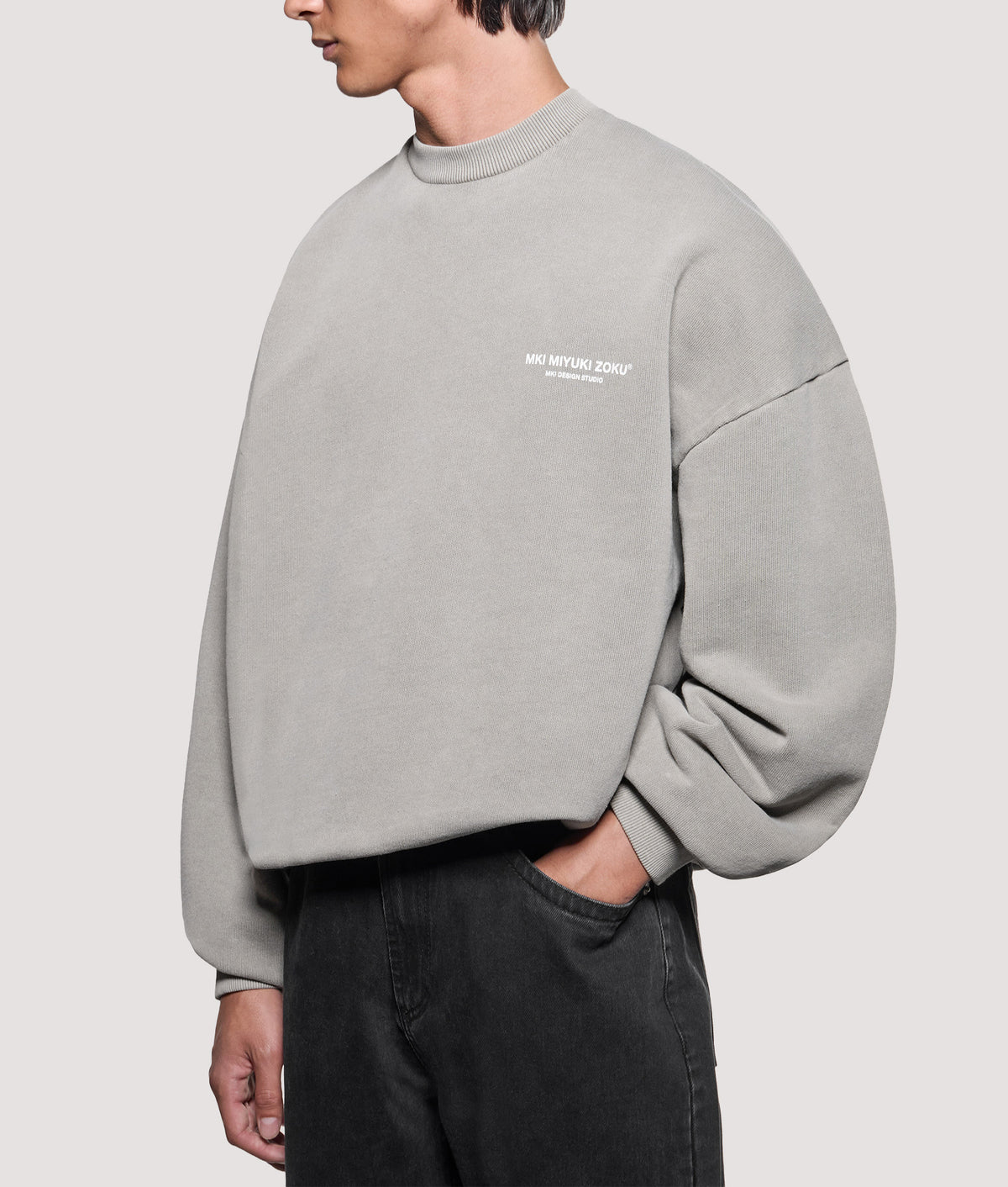 MKI MIYUKI ZOKU Oversized Box Fit Design Studio Crewneck Sweatshirt in Pigment Stone at EQVVS Menswear. Angled model front shot.