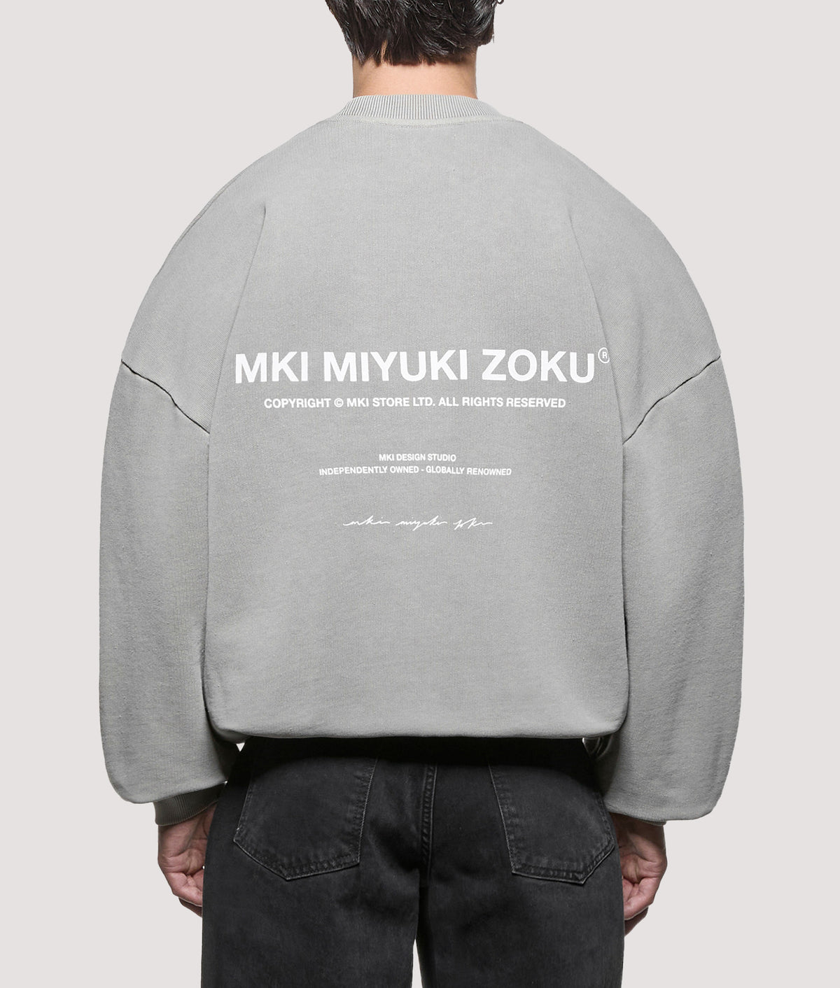 MKI MIYUKI ZOKU Oversized Box Fit Design Studio Crewneck Sweatshirt in Pigment Stone at EQVVS Menswear. Model back shot.