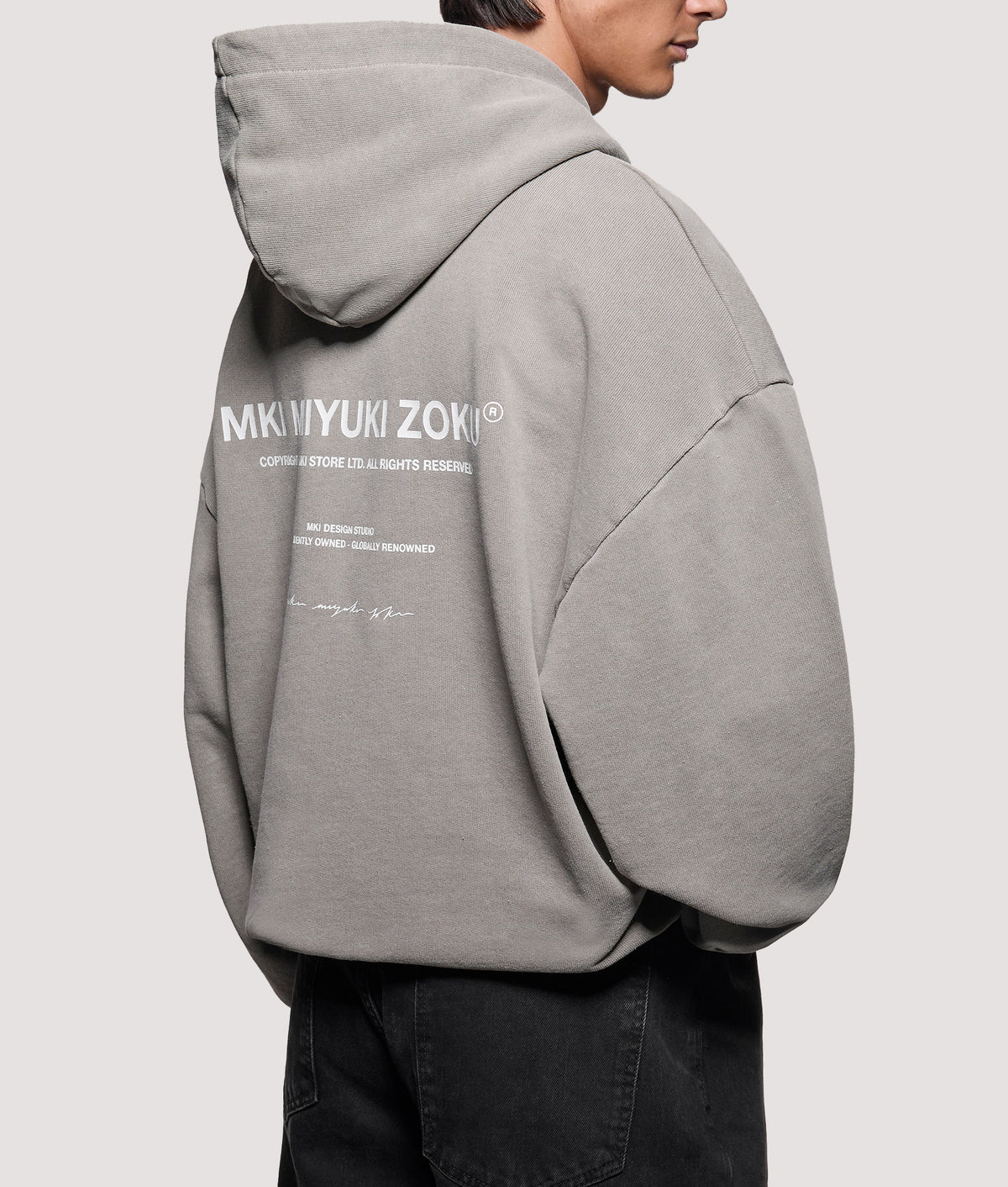 MKI MIYUKI ZOKU Oversized Box Fit Design Studio Hoodie in Pigment Stone at EQVVS Menswear. Angled model back shot.