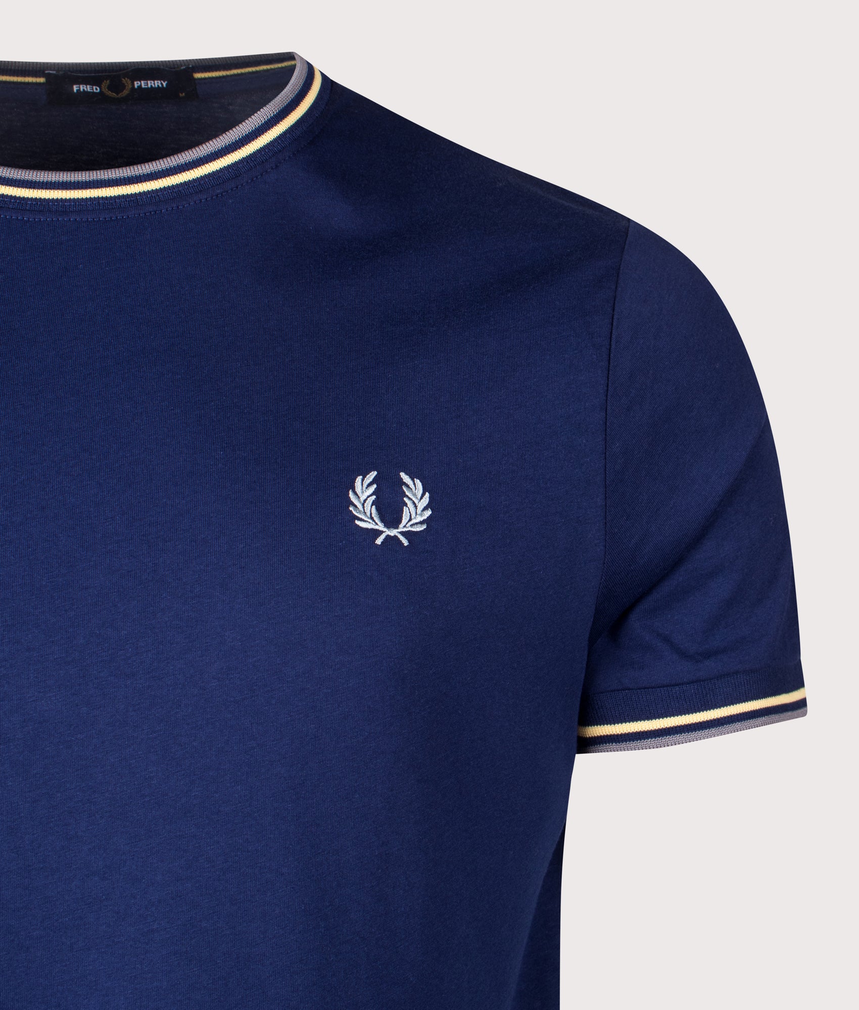 Fred Perry Twin Tipped T-Shirt in French Navy, Champions Gold and Stockport Blue at EQVVS Menswear. Detail shot.