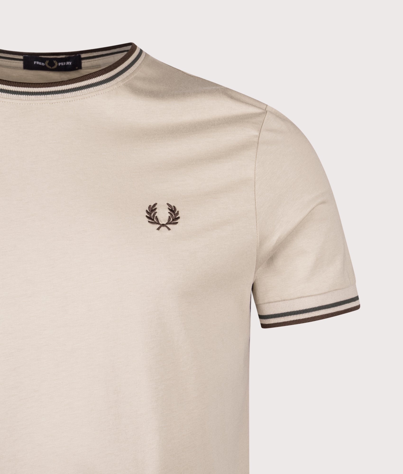 Fred Perry Twin Tipped T-Shirt in Warm Oat, Court Green and Burnt Tobacco at EQVVS Menswear. Detail shot.