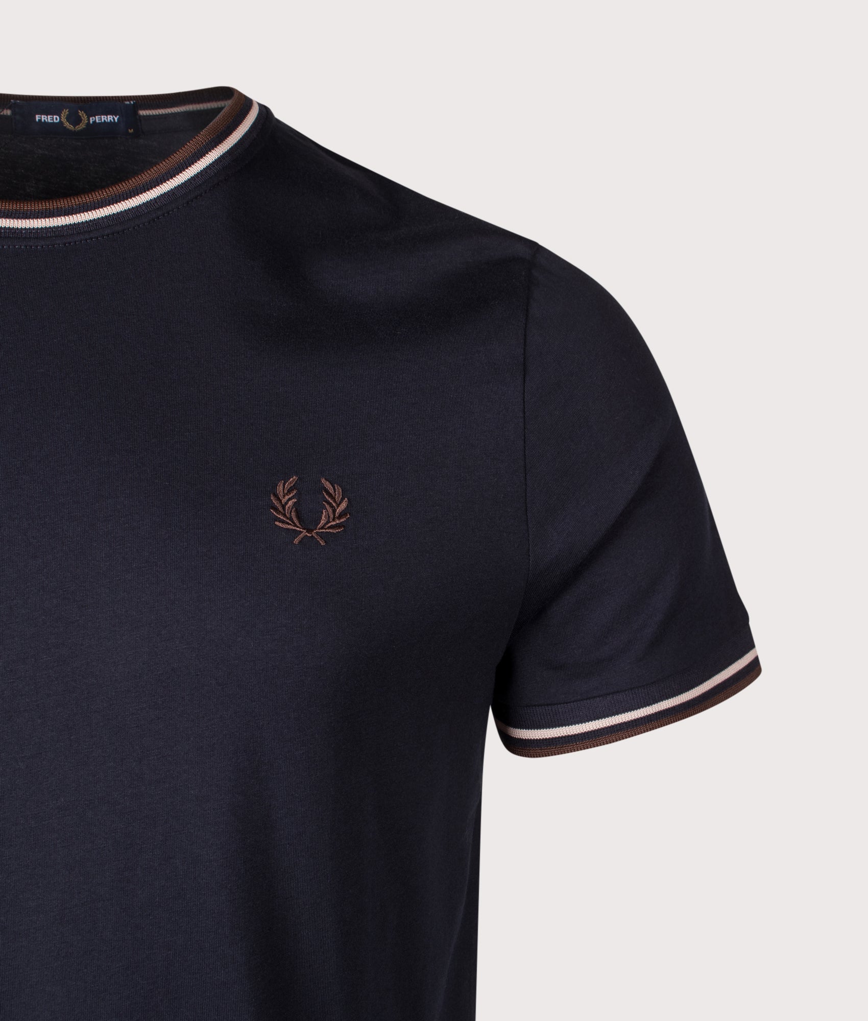 Fred Perry essential, the Twin Tipped T-Shirt in Navy, Warm Oat and Burnt Tobacco at EQVVS Menswear. Detail shot.