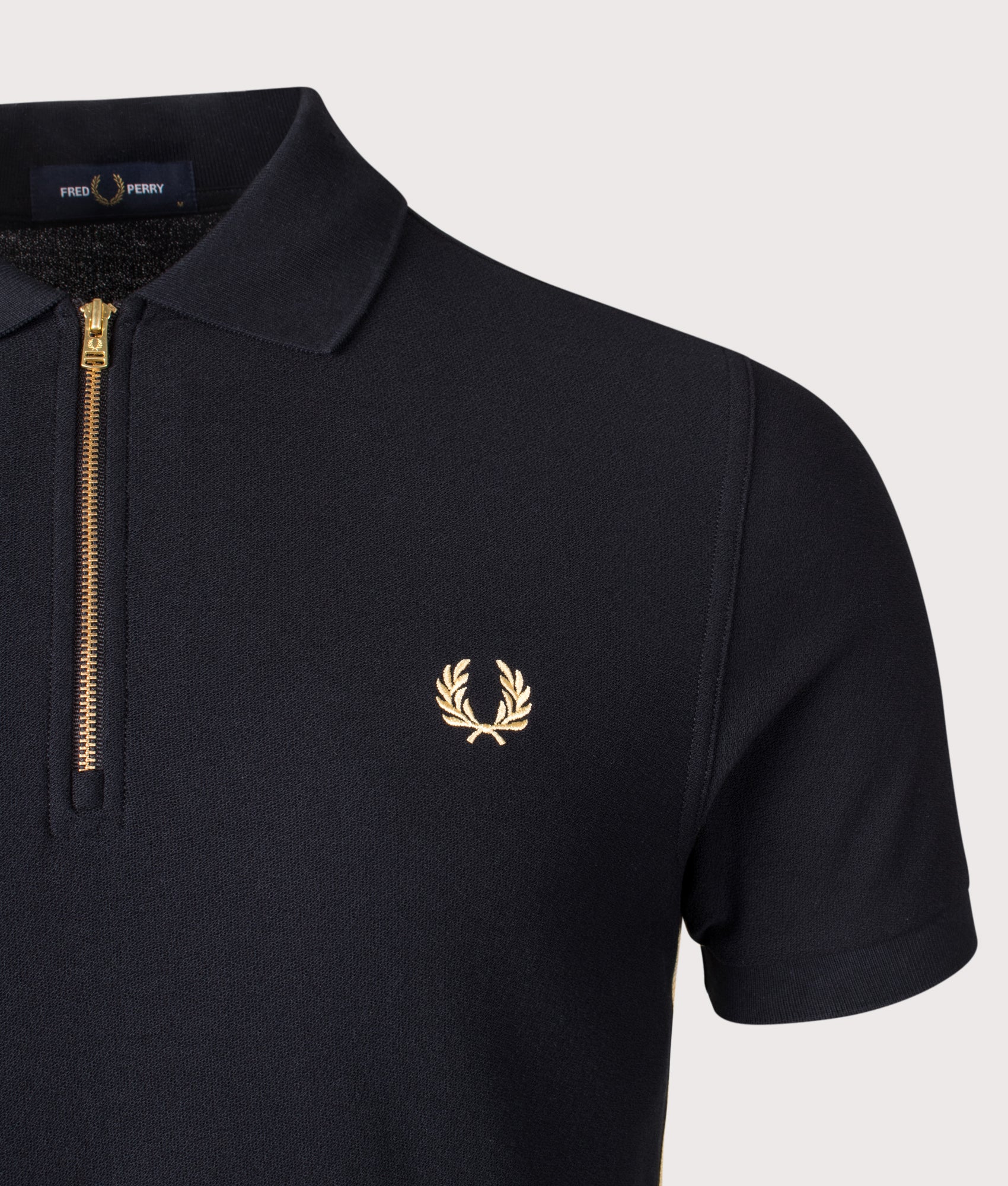 Fred Perry Stripe Tape Zip Neck Polo Shirt in Black and Champagne at EQVVS Menswear. Detail shot.