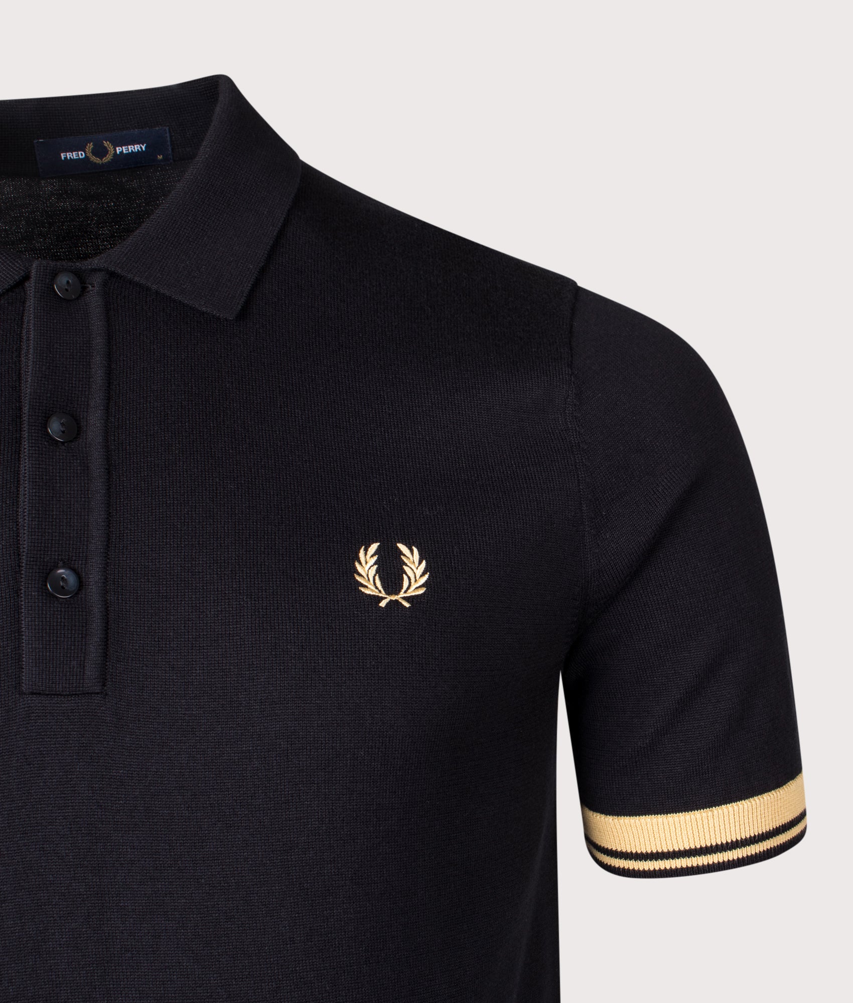 Fred Perry Contrast Cuff Knitted Polo Shirt in Black and Champagne at EQVVS Menswear. Detail shot.