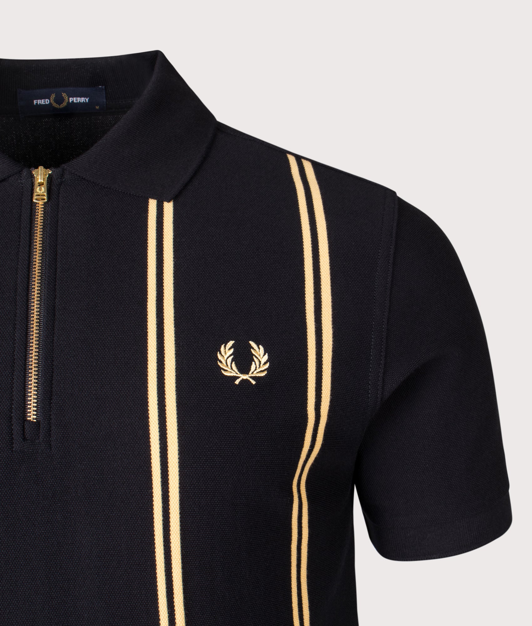 Fred Perry Vertical Stripe Zip Neck Polo Shirt in Black and Champagne at EQVVS Menswear. Detail shot.