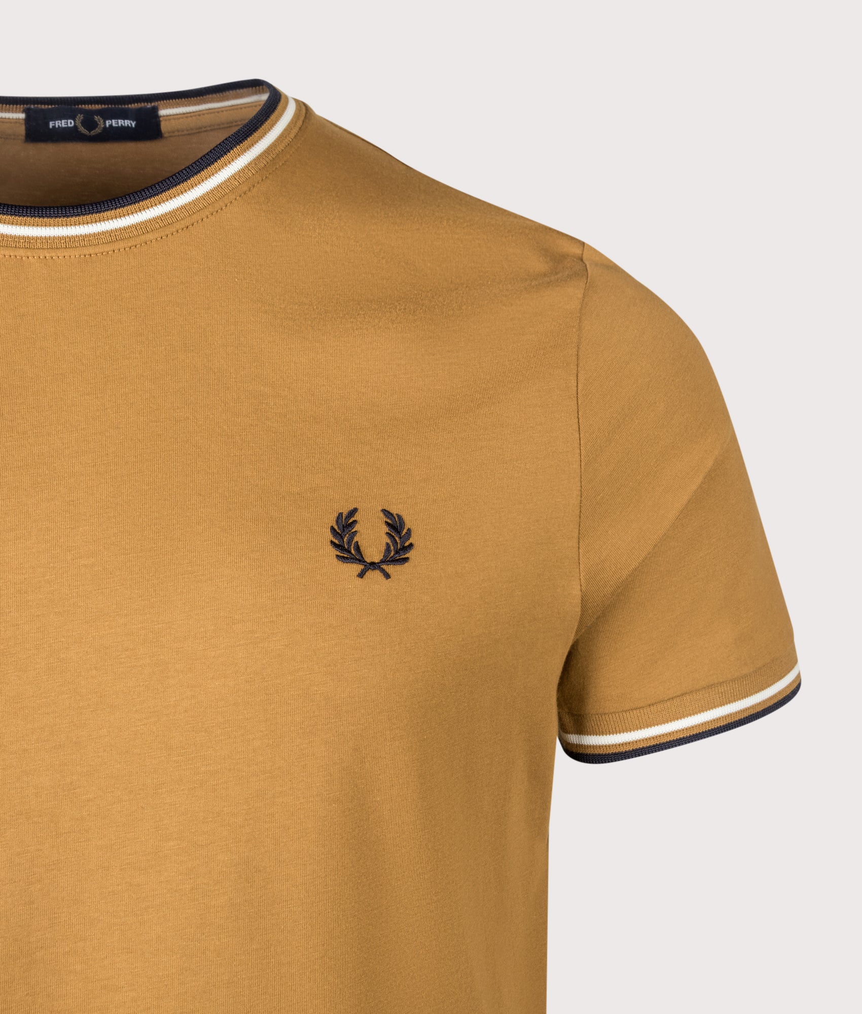 Fred Perry Twin Tipped T-Shirt in Dark Caramel, Ecru and Navy at EQVVS Menswear. Detail shot.