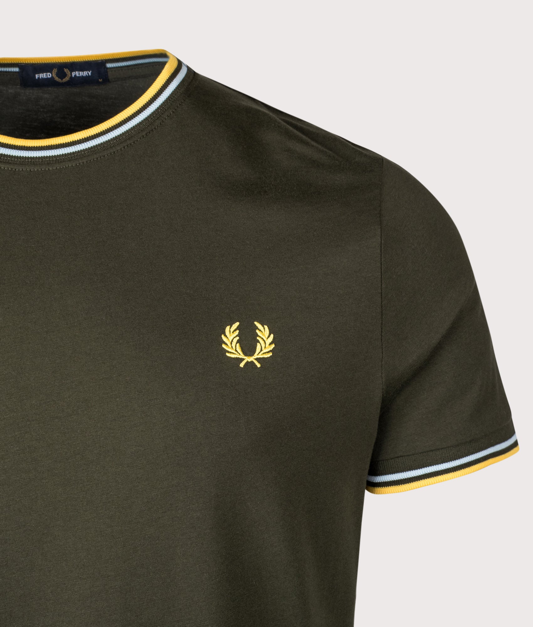 Fred Perry Twin Tipped T-Shirt in Hunting Green, Light Ice and Lemon Barley at EQVVS Menswear. Detail shot.