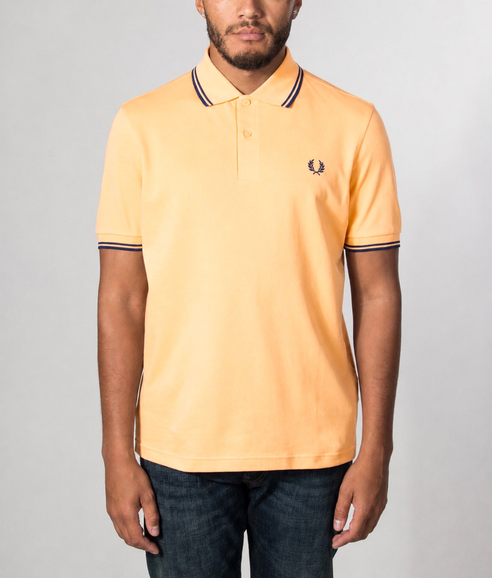 Fred Perry Twin Tipped Polo Shirt in Peach and French Navy at EQVVS Menswear. Model front shot.