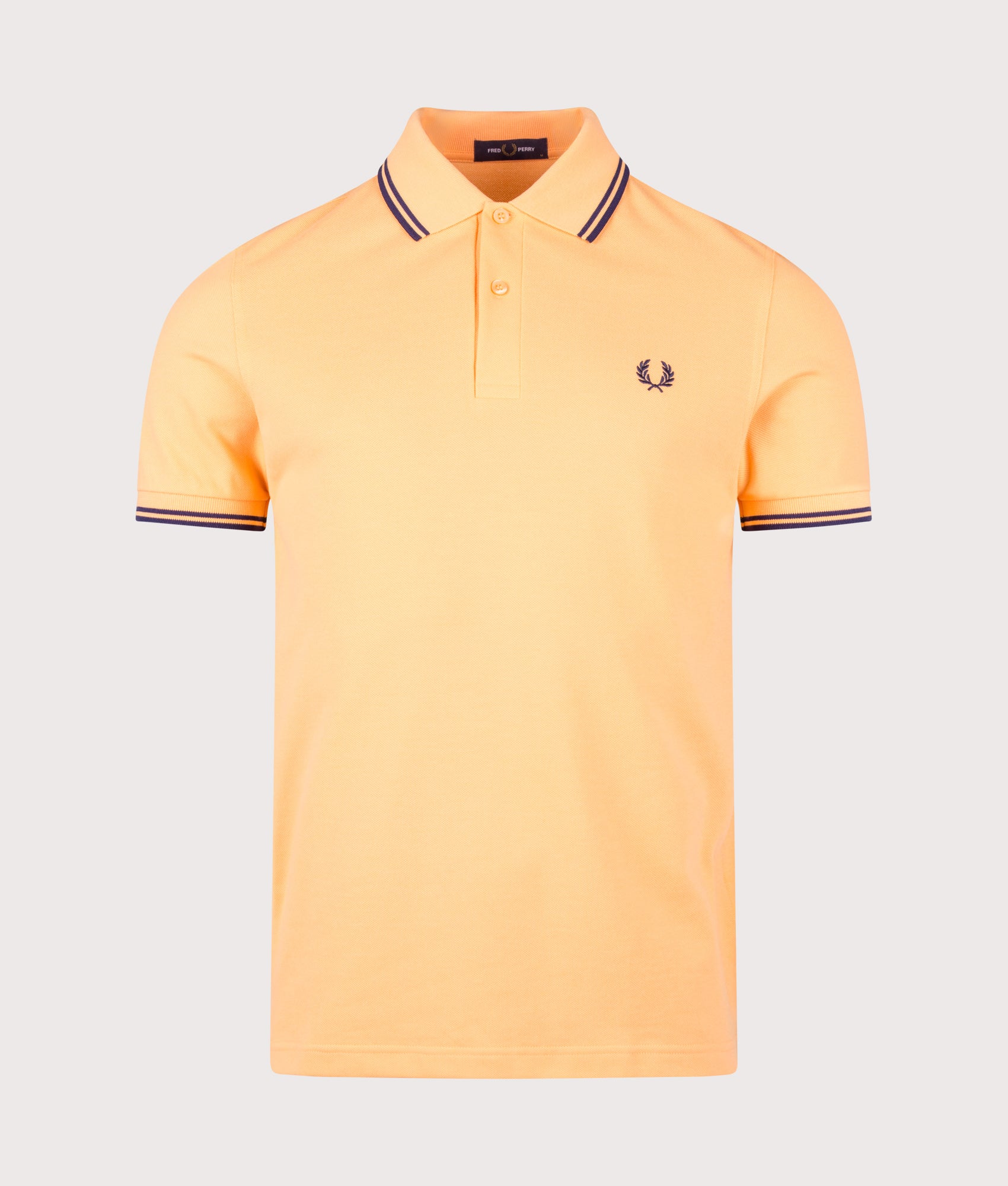 Fred Perry Twin Tipped Polo Shirt in Peach and French Navy at EQVVS Menswear. Front shot.