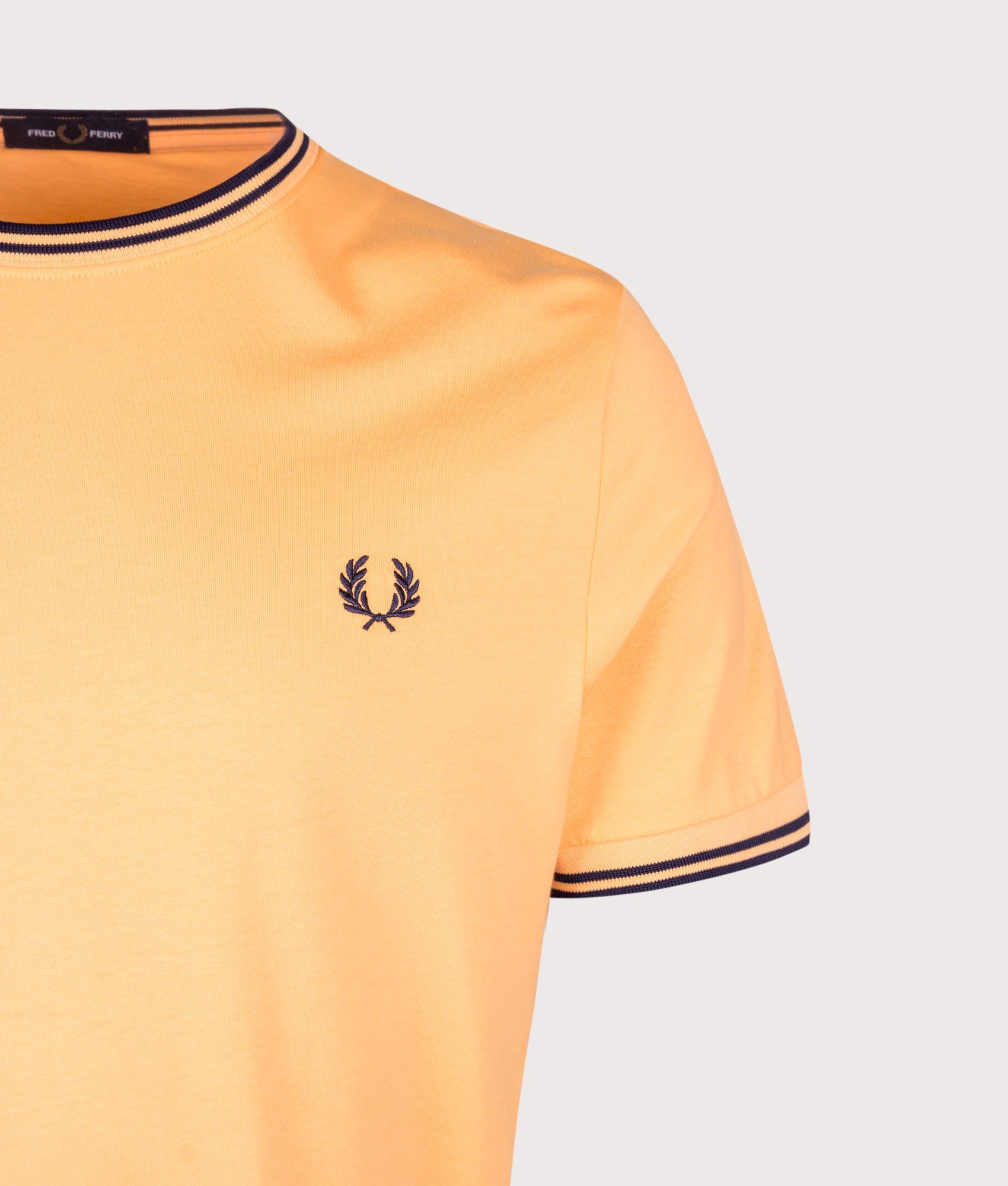 Fred Perry Regular Fit Twin Tipped T-Shirt in Peach and French Navy at EQVVS Menswear. Detail shot.