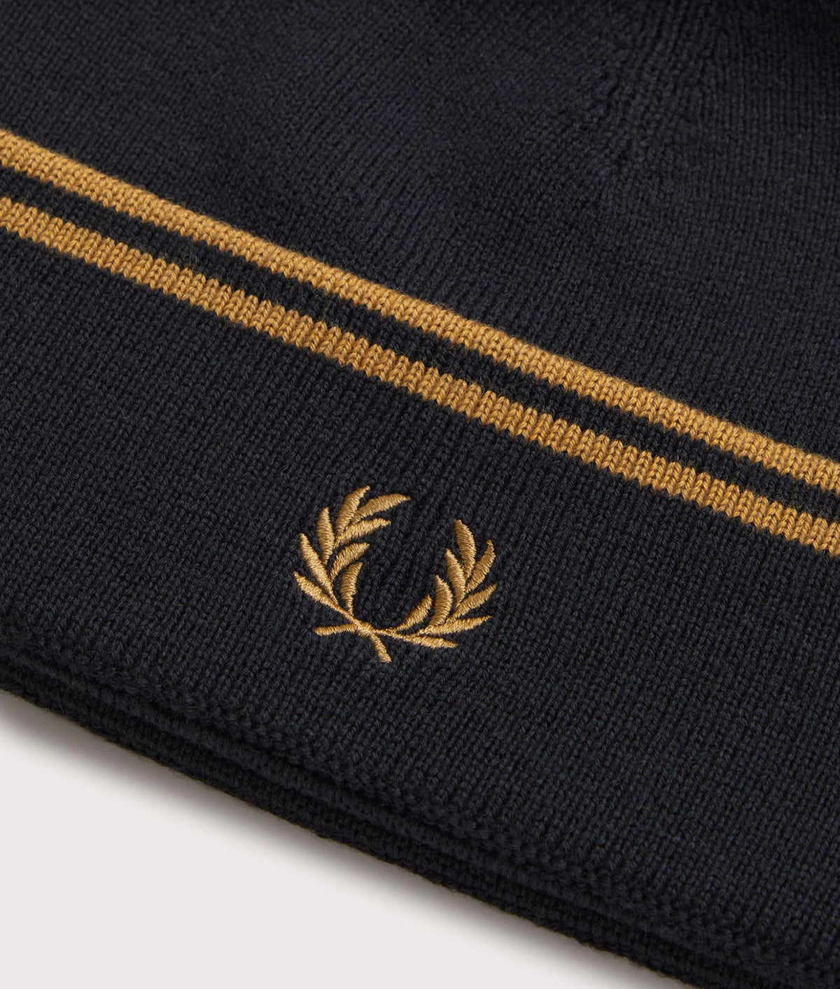 Fred Perry Twin Tipped Merino Wool Beanie in Black and Dark Caramel at EQVVS Menswear. Detail shot.