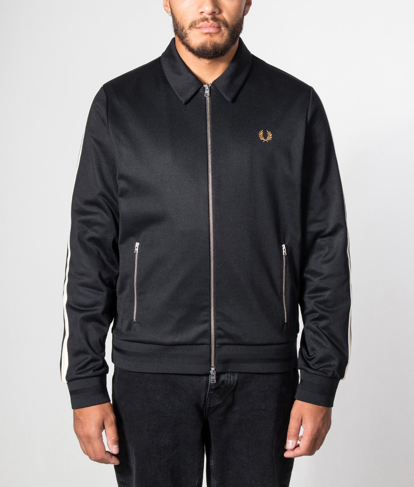 Fred Perry Regular Fit Tipped Tape Track Jacket in Black at EQVVS Menswear. Model front shot.