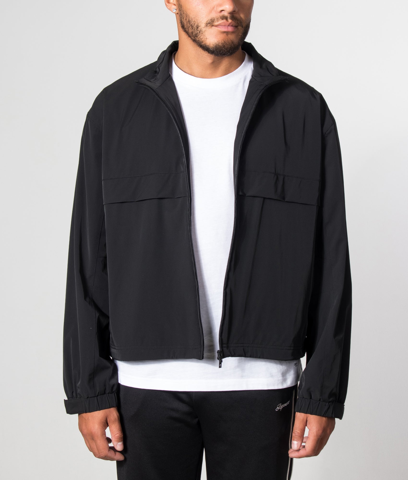 Represent Oversized Initial Nylon Track Jacket in Jet Black at EQVVS Menswear. Model open jacket shot.