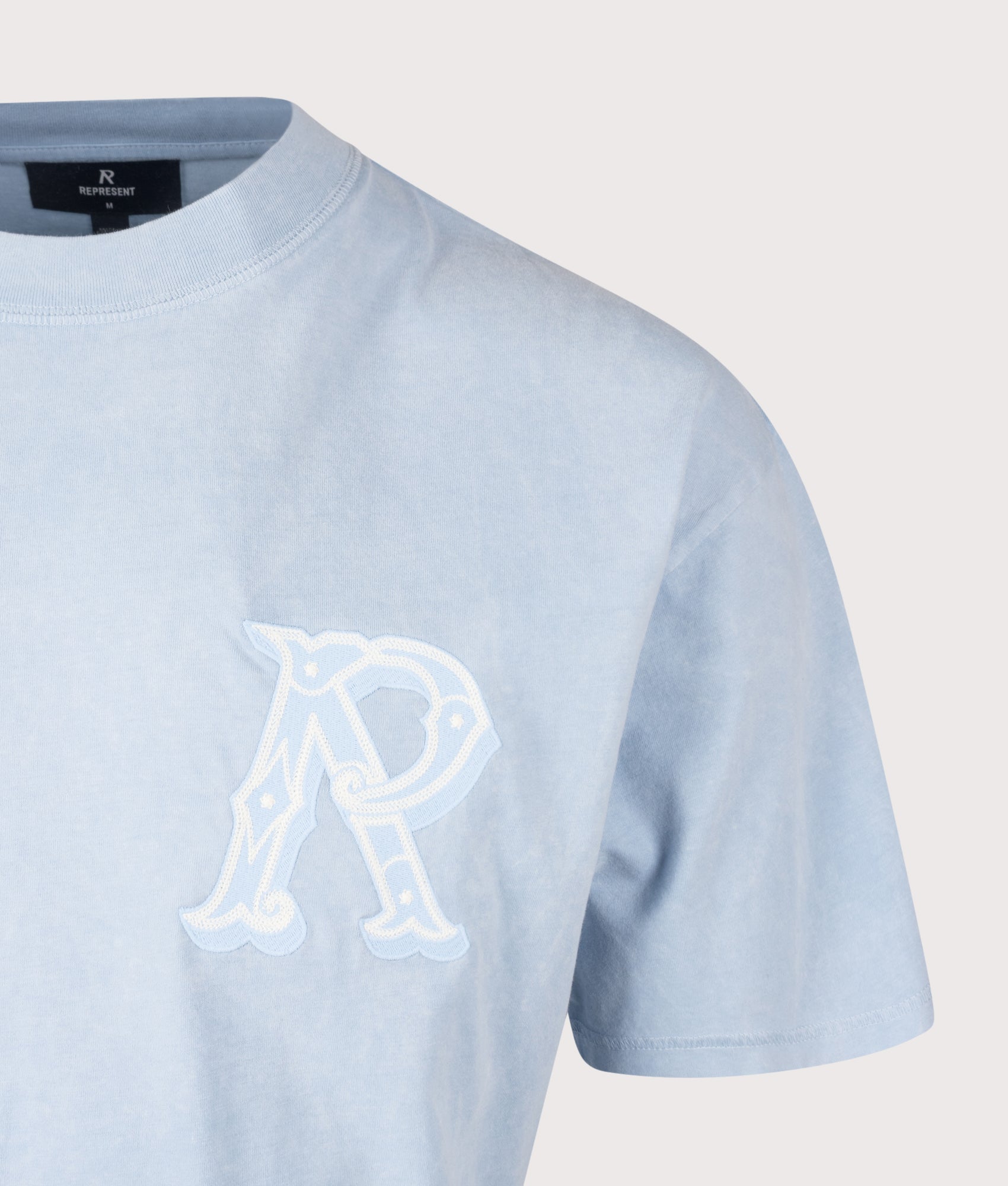 REPRESENT Oversized Fit Western Initial T-Shirt in Mountain Bluebird at EQVVS Menswear. Detail shot.