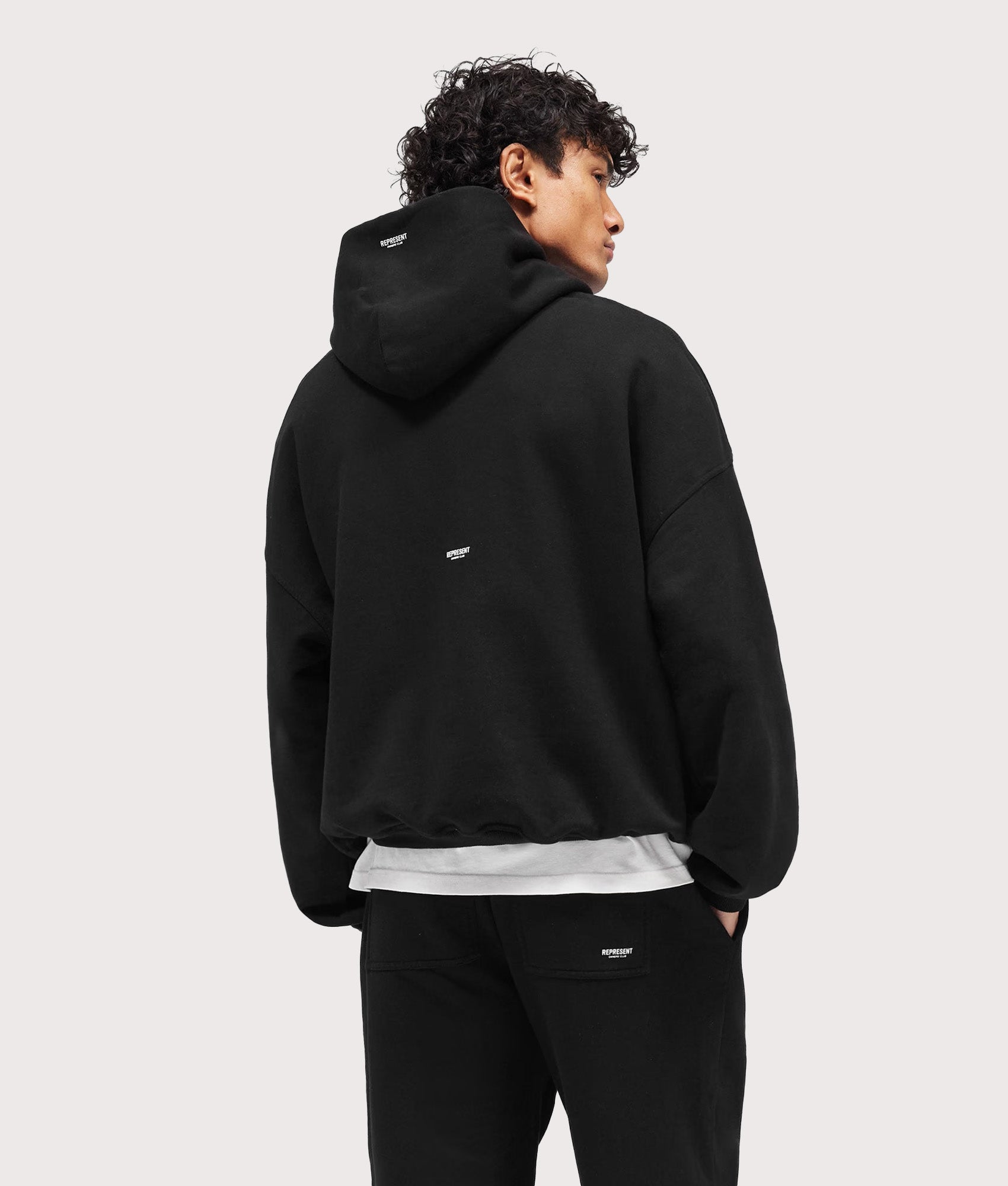 Represent Oversized Micro Owners Club Hoodie in Jet Black at EQVVS Menswear. Model back shot.