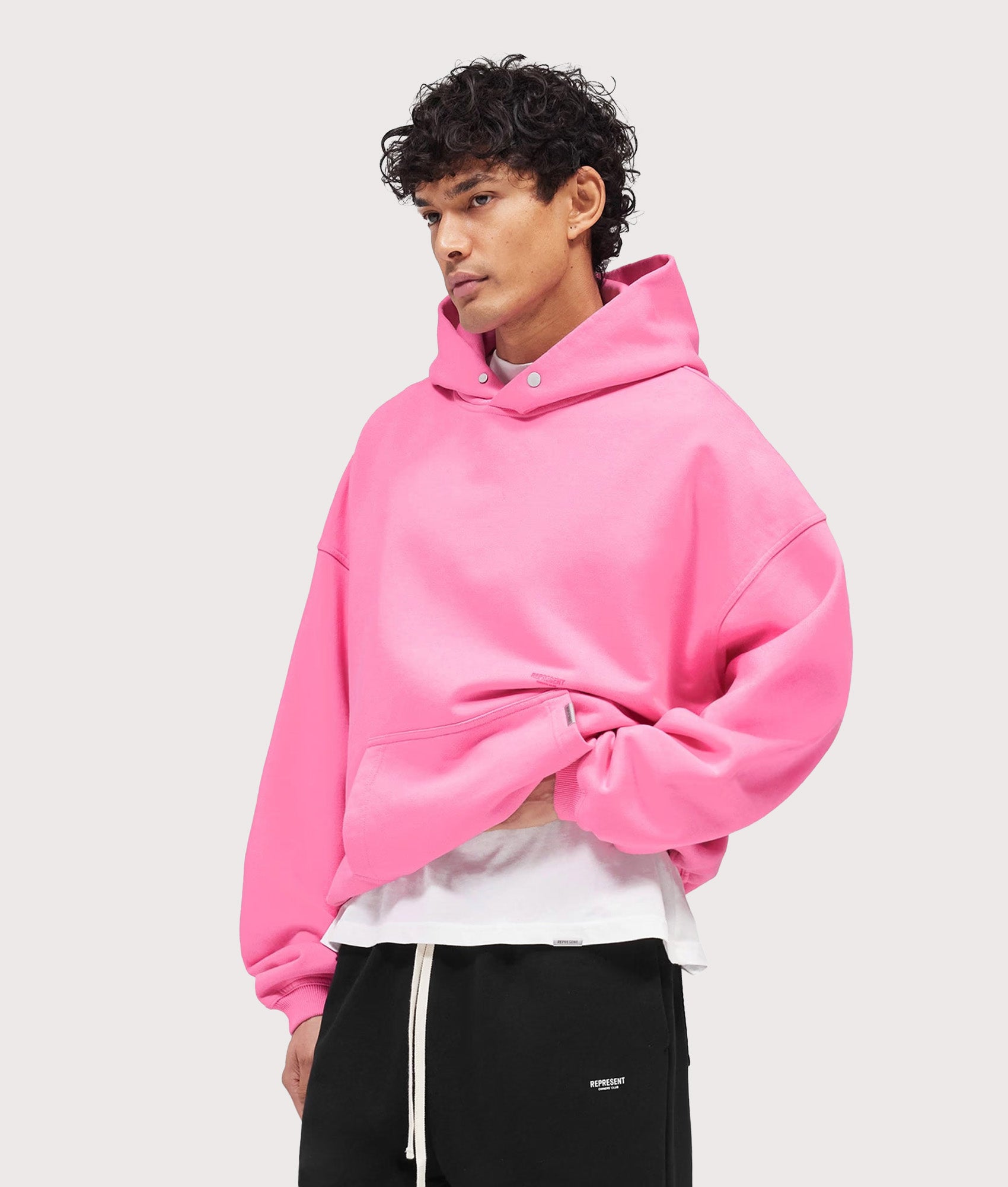 Represent Oversized Micro Owners Club Hoodie in Pink at EQVVS Menswear. Angled model front shot.