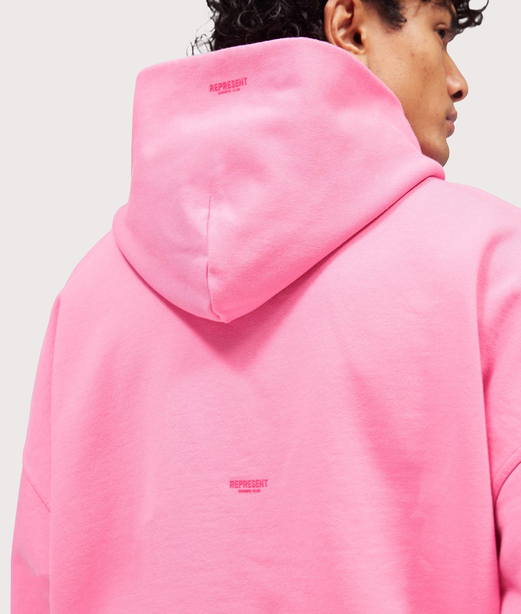 Represent Oversized Micro Owners Club Hoodie in Pink at EQVVS Menswear. Model back detail shot.