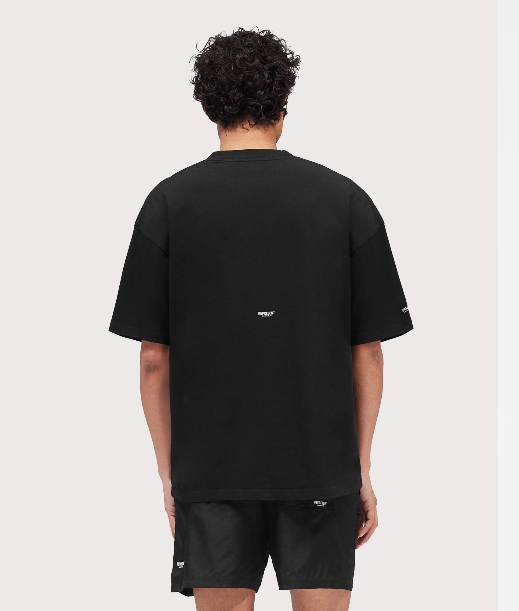 Represent Oversized Micro Owners Club T-Shirt in Jet Black at EQVVS Menswear. Model back shot.