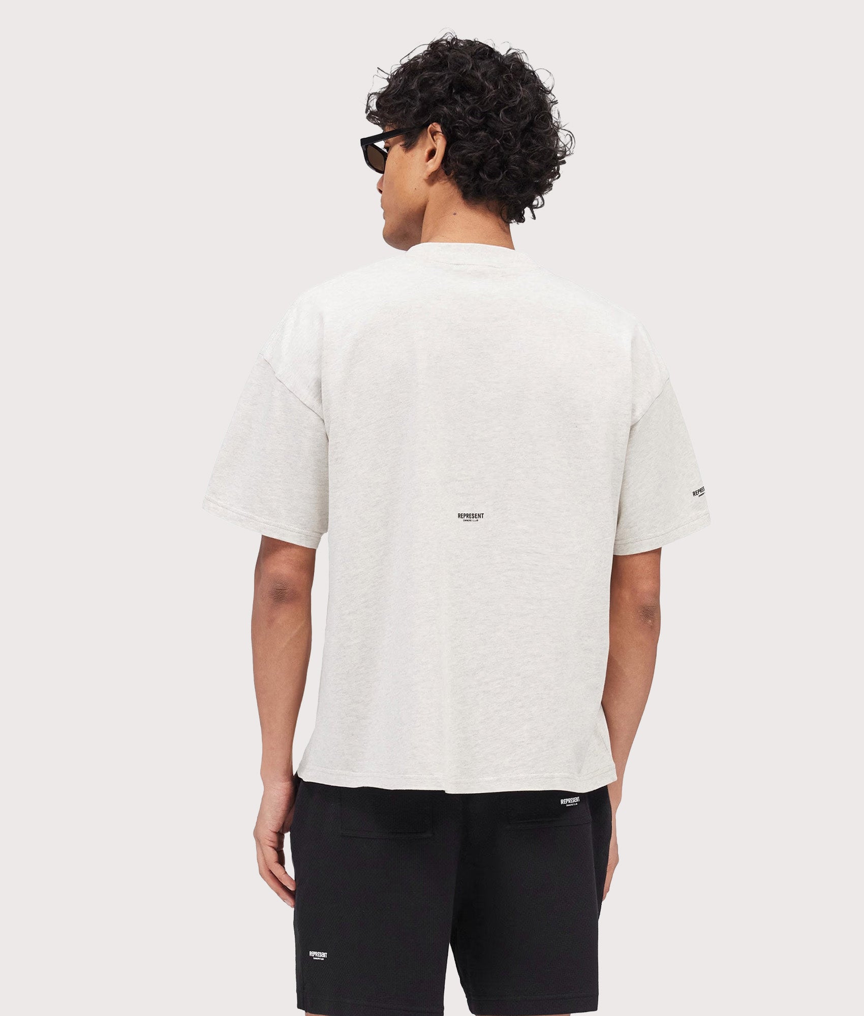 Represent Oversized Micro Owners Club T-Shirt in Cream Marl at EQVVS Menswear. Model back shot.