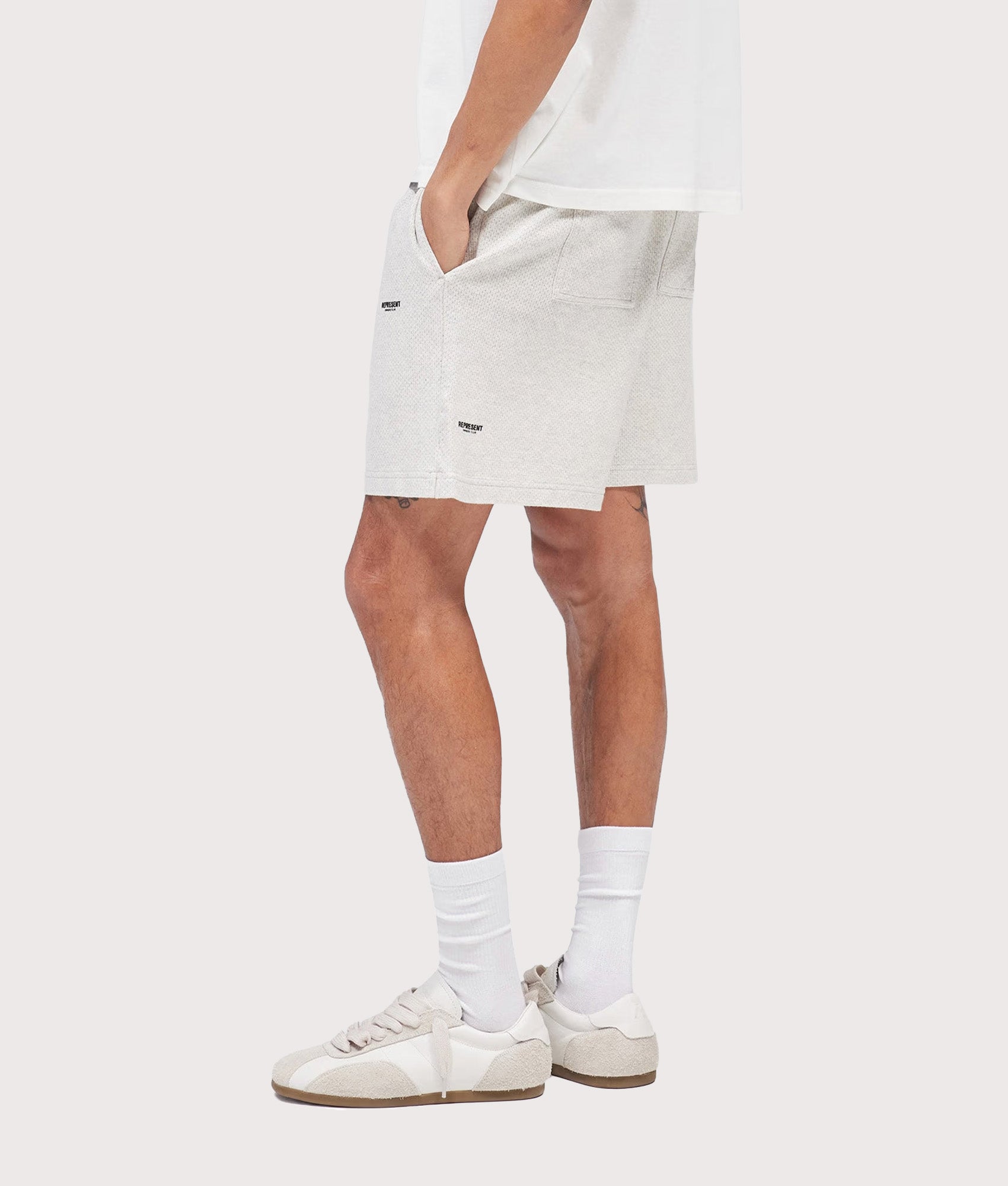 Represent Relaxed fit Micro Owners Club Shorts in Cream Marl at EQVVS Menswear. Model side shot.