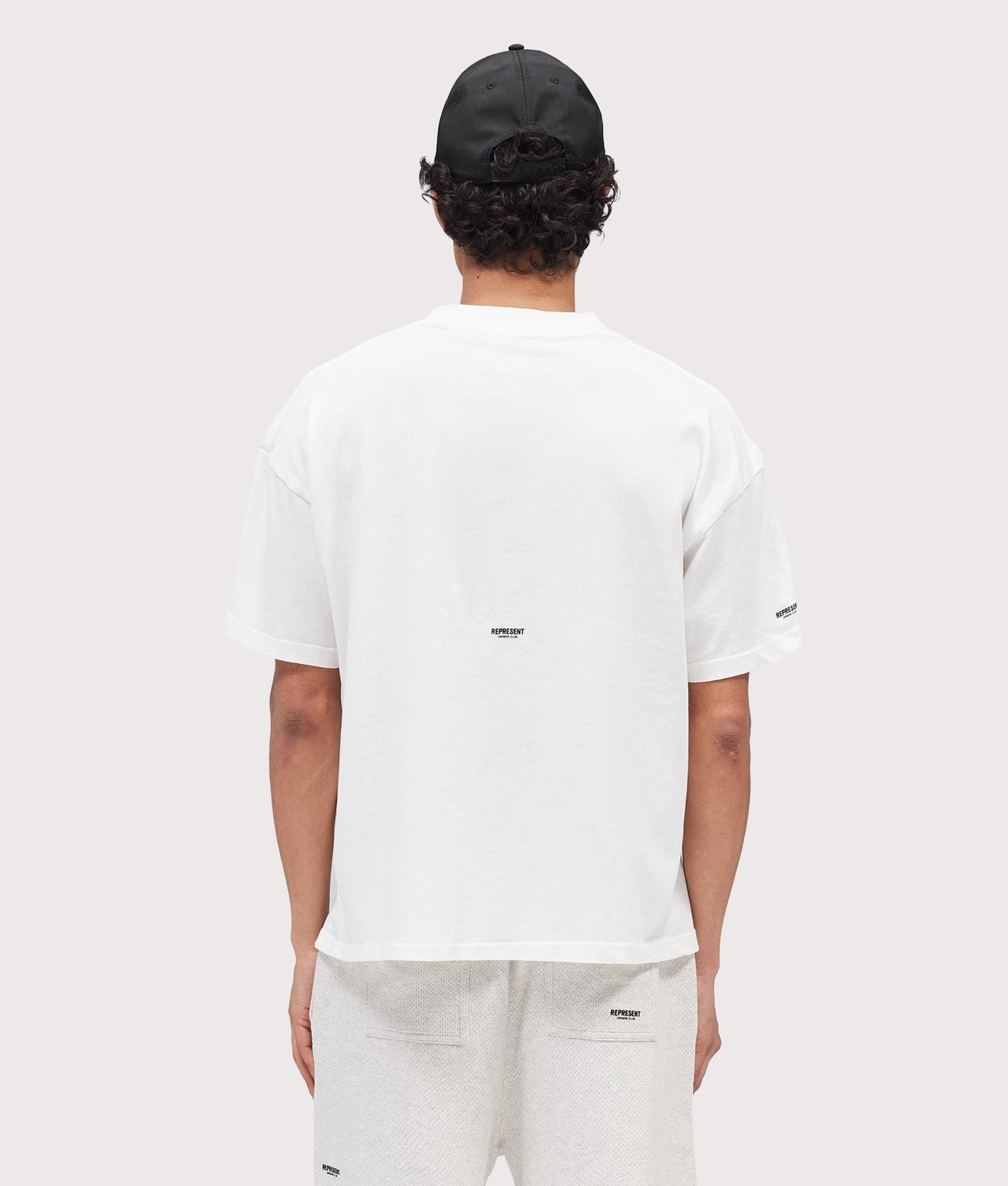 Represent Oversized Micro Owners Club T-Shirt in Flat White at EQVVS Menswear. Model back shot.