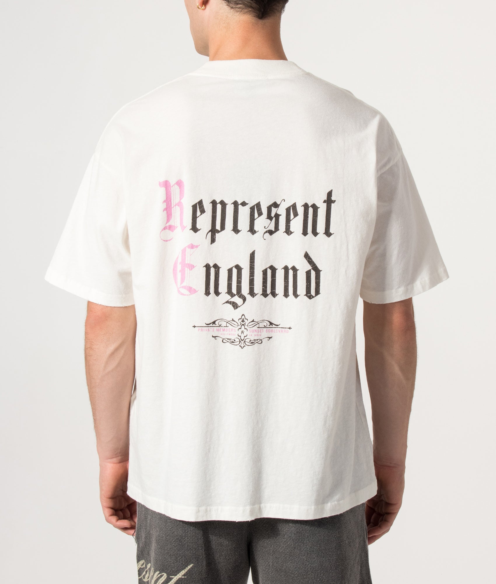 Represent Oversized Fit Private Members T-Shirt in Flat White at EQVVS Menswear. Model back shot.