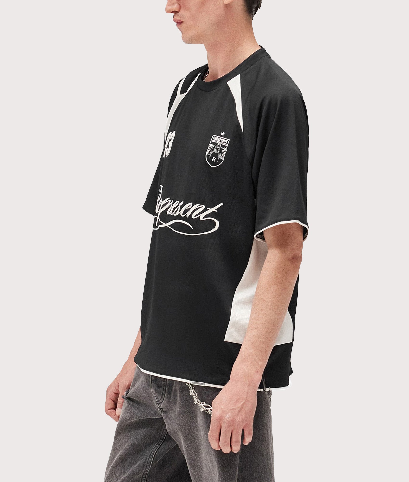 Represent Oversized Star Football Top in Jet Black at EQVVS Menswear. Angled model shot.