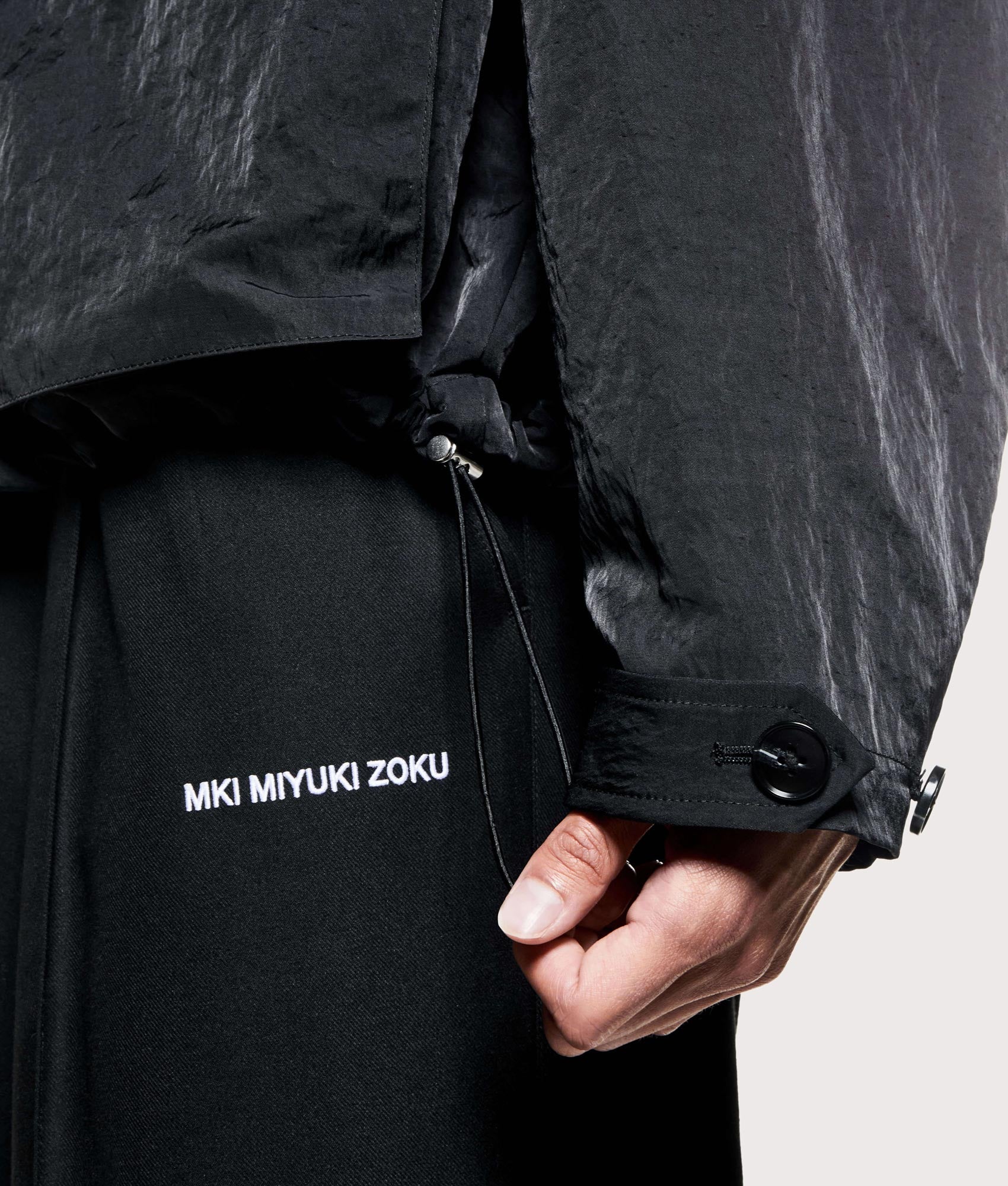 MKI MIYUKI ZOKU Silky nylon box overshirt in black at EQVVS Menswear. Adjustable hem detail. 