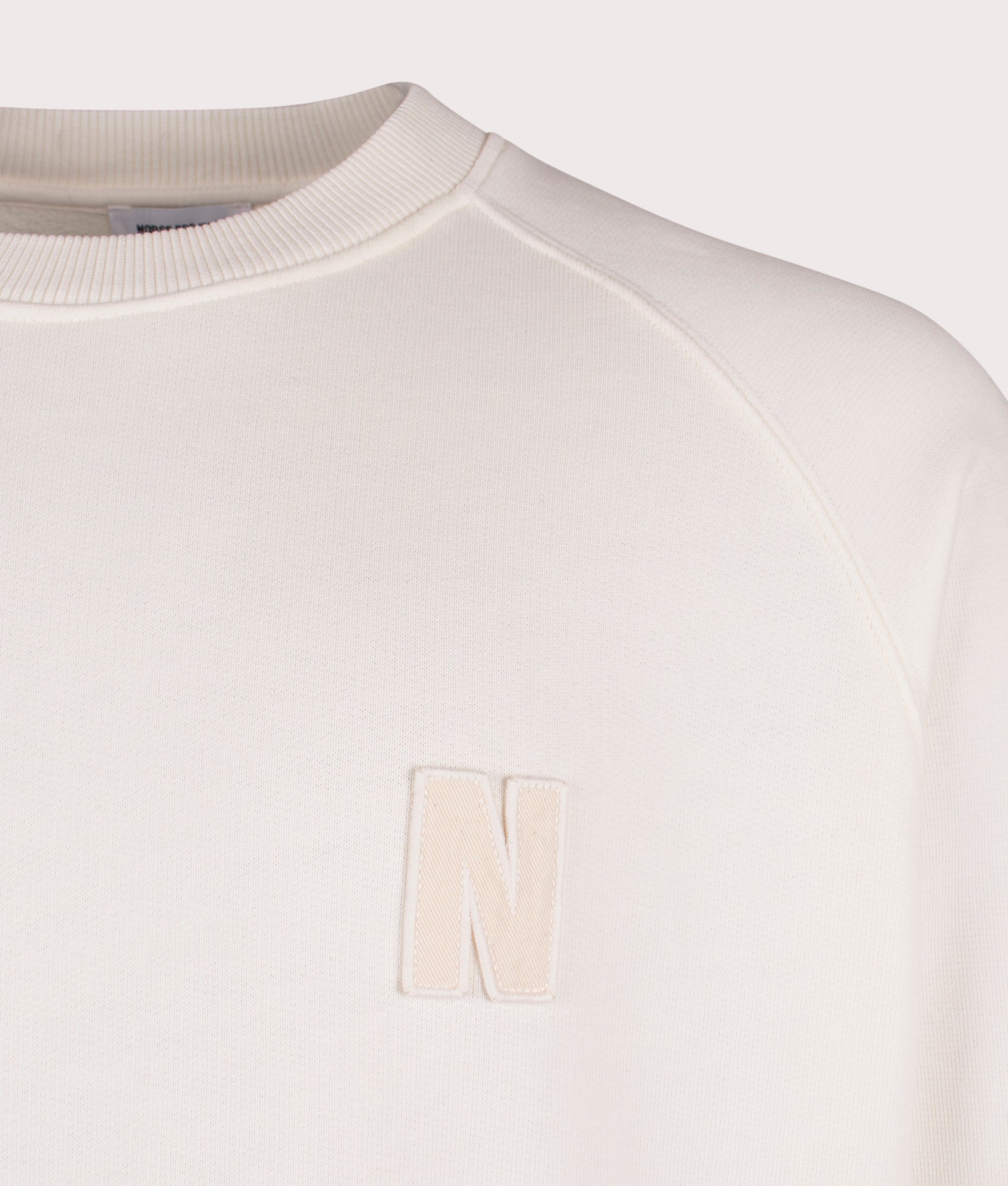 Norse Projects Relaxed Fit Marten Raglan N Patch Sweatshirt in Ecru at EQVVS Menswear Detail Shot