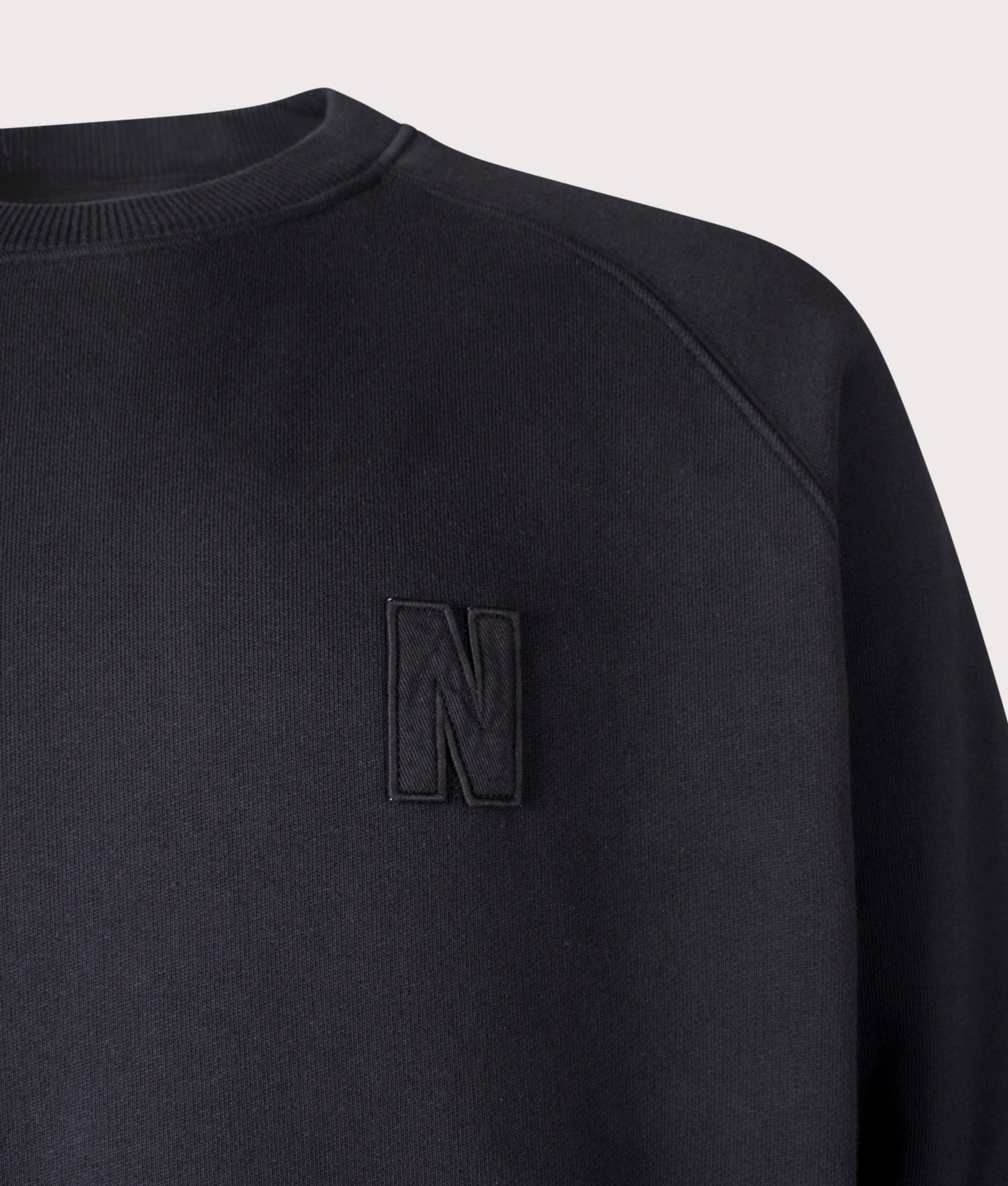 Norse Projects Relaxed Fit Marten Raglan N Patch Sweatshirt in Black Organic Cotton at EQVVS Menswear Detail Shot
