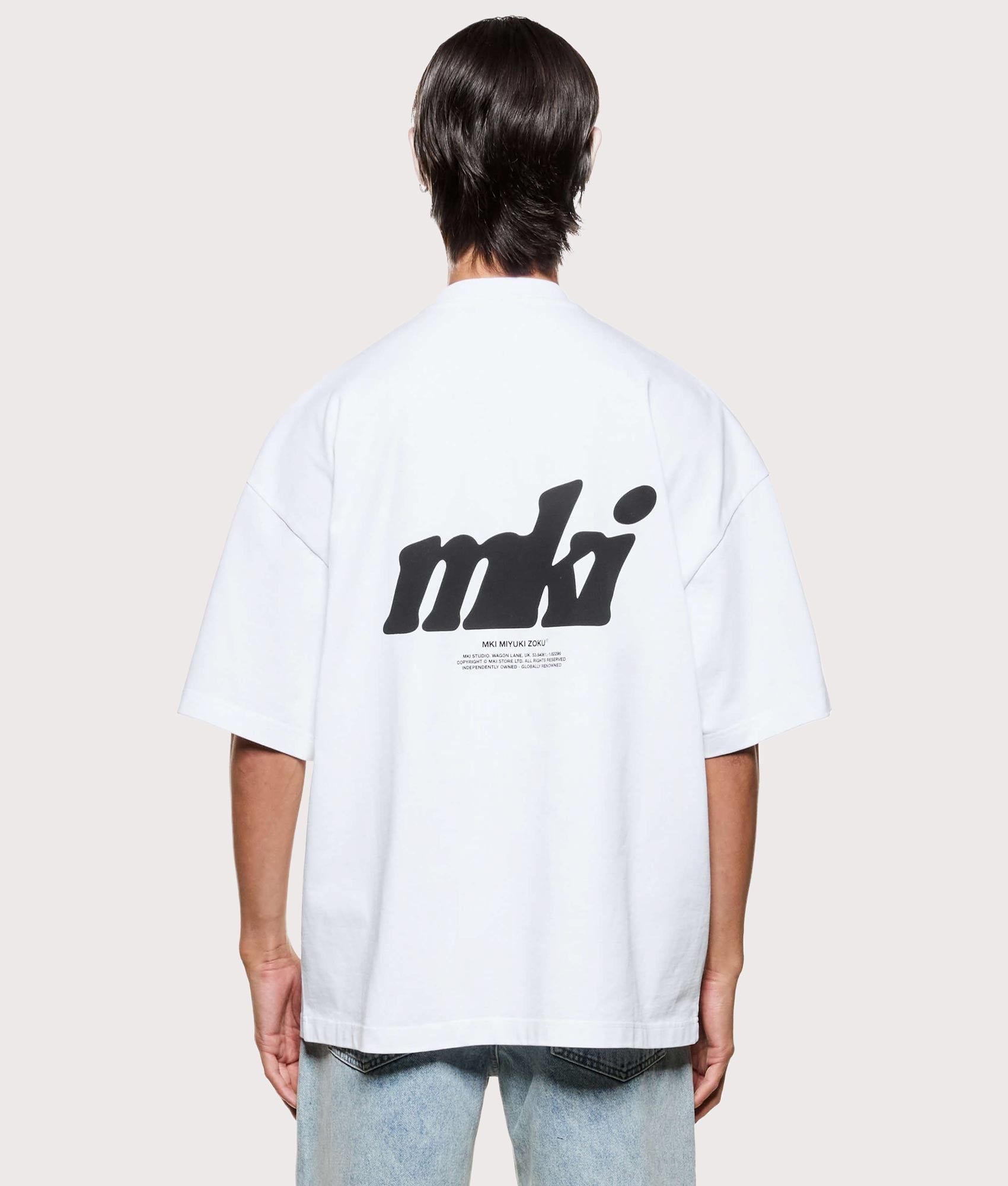 MKI MIYUKI ZOKU Stamp T-Shirt in white at EQVVS Menswear. Model back shot.