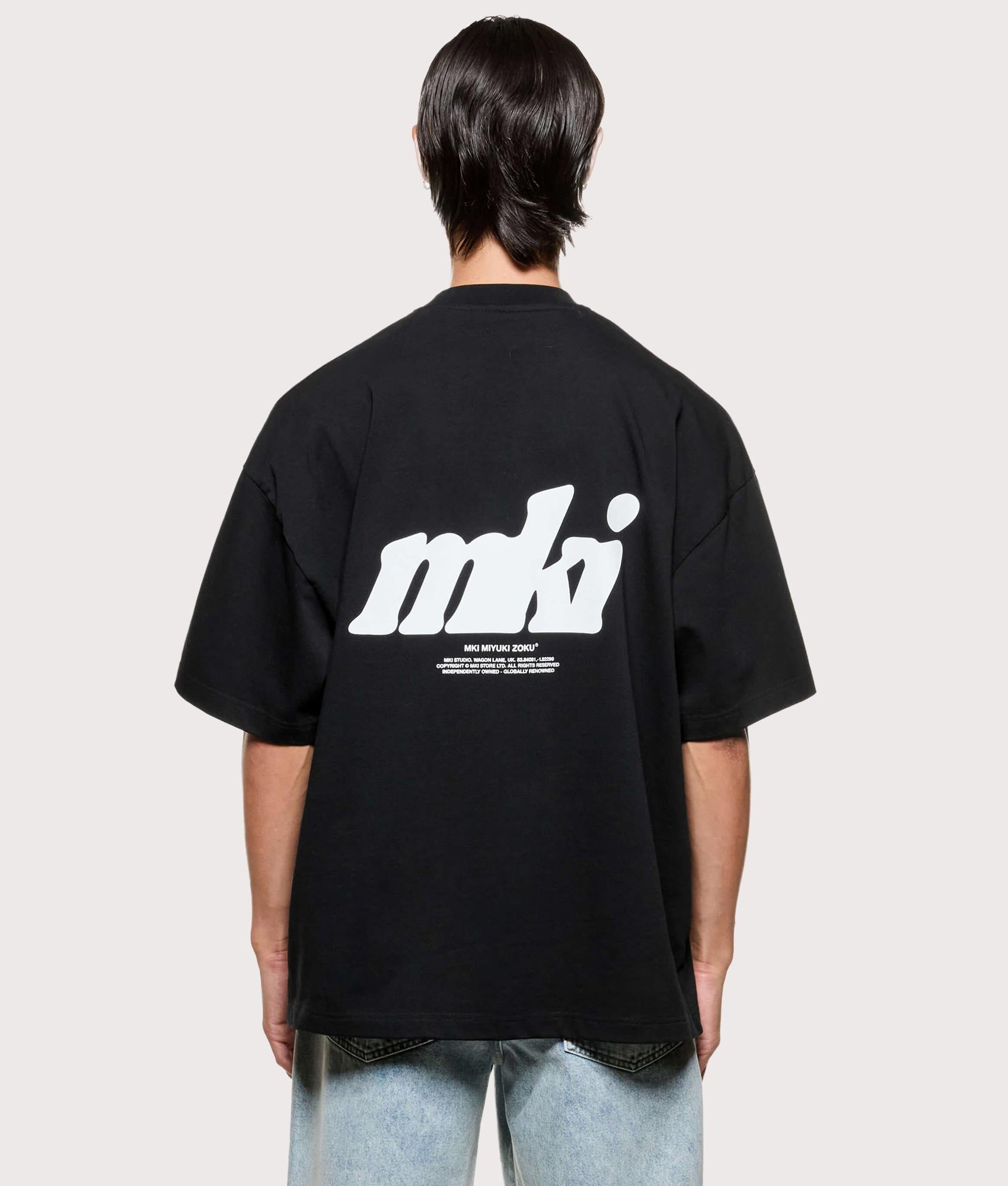MKI MIYUKI ZOKU Stamp T-Shirt in Black at EQVVS Menswear. Model back shot.
