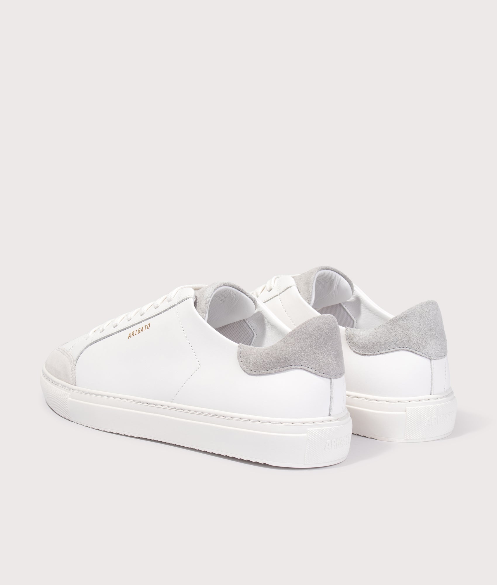 Axel Arigato Clean 90 Triple Sneakers in White/Grey at EQVVS Menswear. Angled back shot.