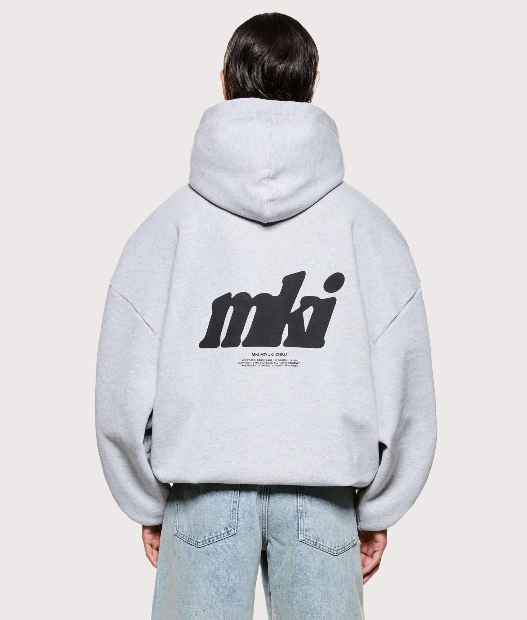 MKI MIYUKI ZOKU Stamp Hoodie in Grey at EQVVS Menswear. Model back shot.