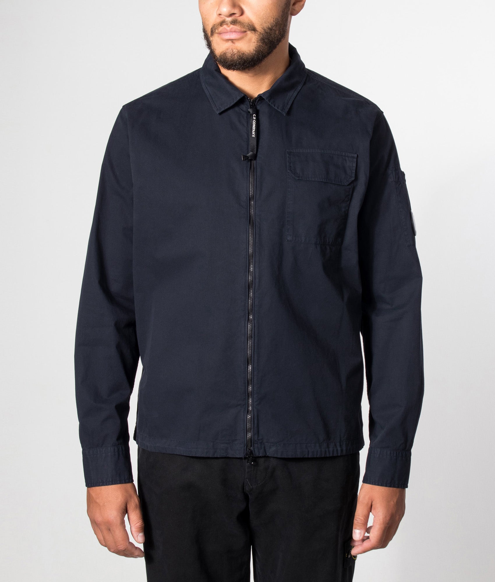 C.P. Company Organic Gabardine Zipped Lens Overshirt in Total Eclipse at EQVVS Menswear. Model front shot.