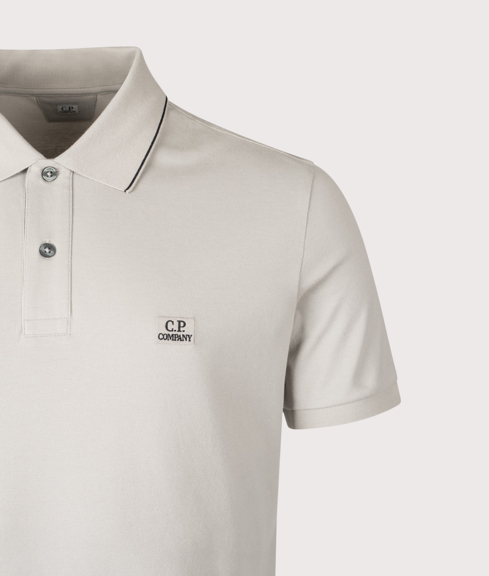 C.P. Company Stretch Piquet Short Sleeve Logo Polo Shirt in Dove at EQVVS Menswear. Detail shot.