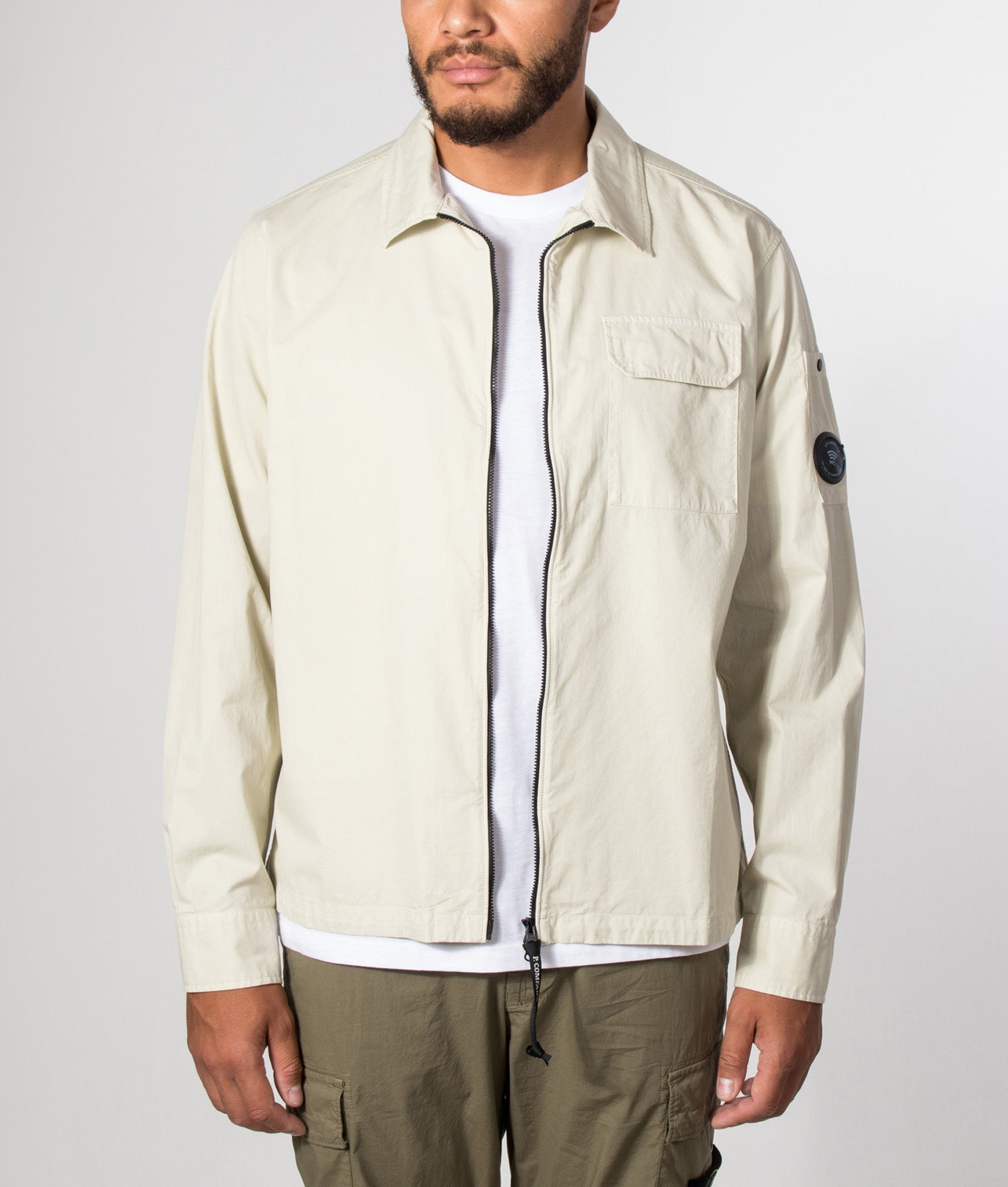 C.P. Company Organic Gabardine Zipped Lens Overshirt in Silver Birch at EQVVS Menswear. Model front shot.