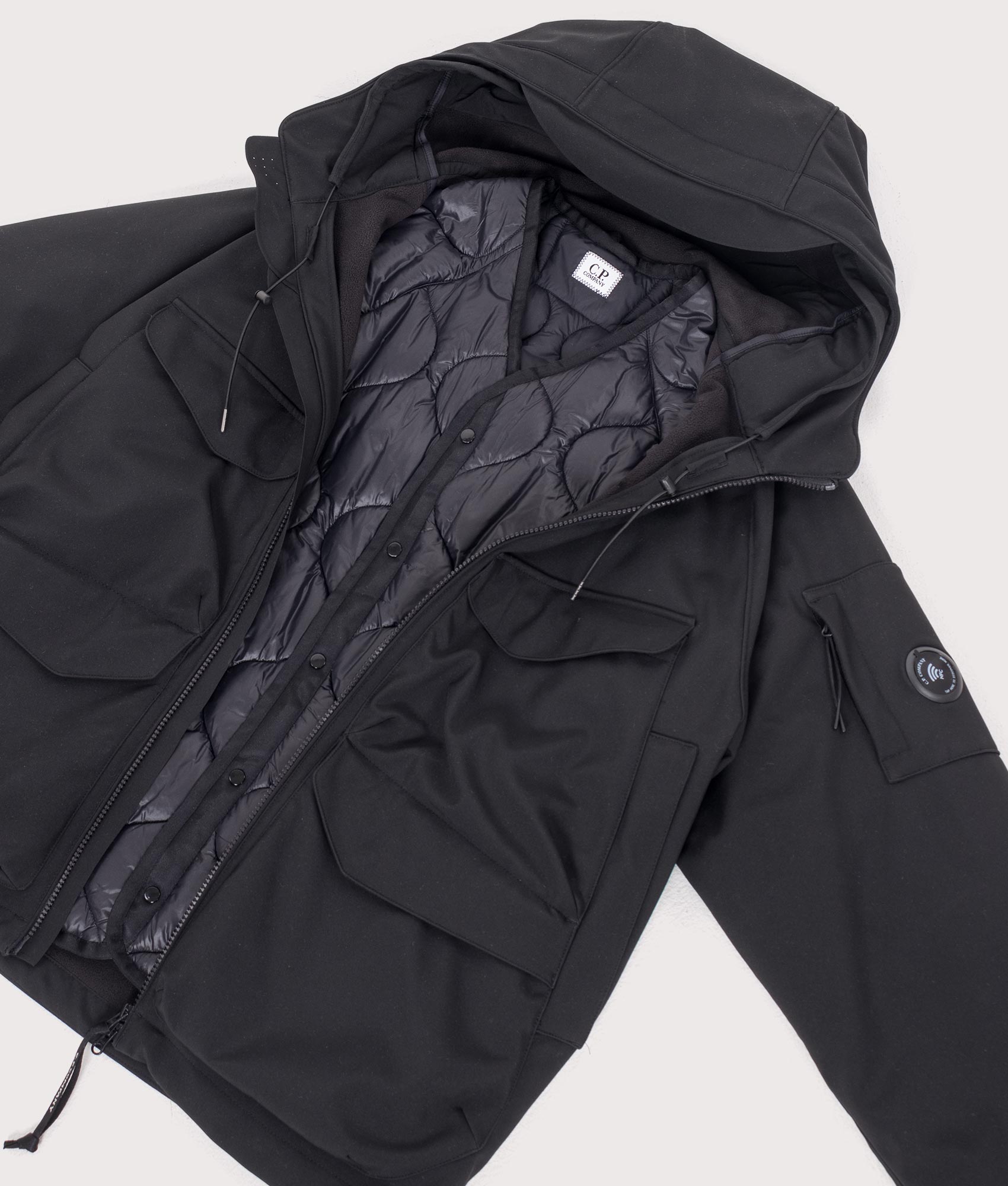 C.P. Company C.P. Shell-R Padded Hooded Lens Jacket in Black at EQVVS Menswear. Flat liner shot.