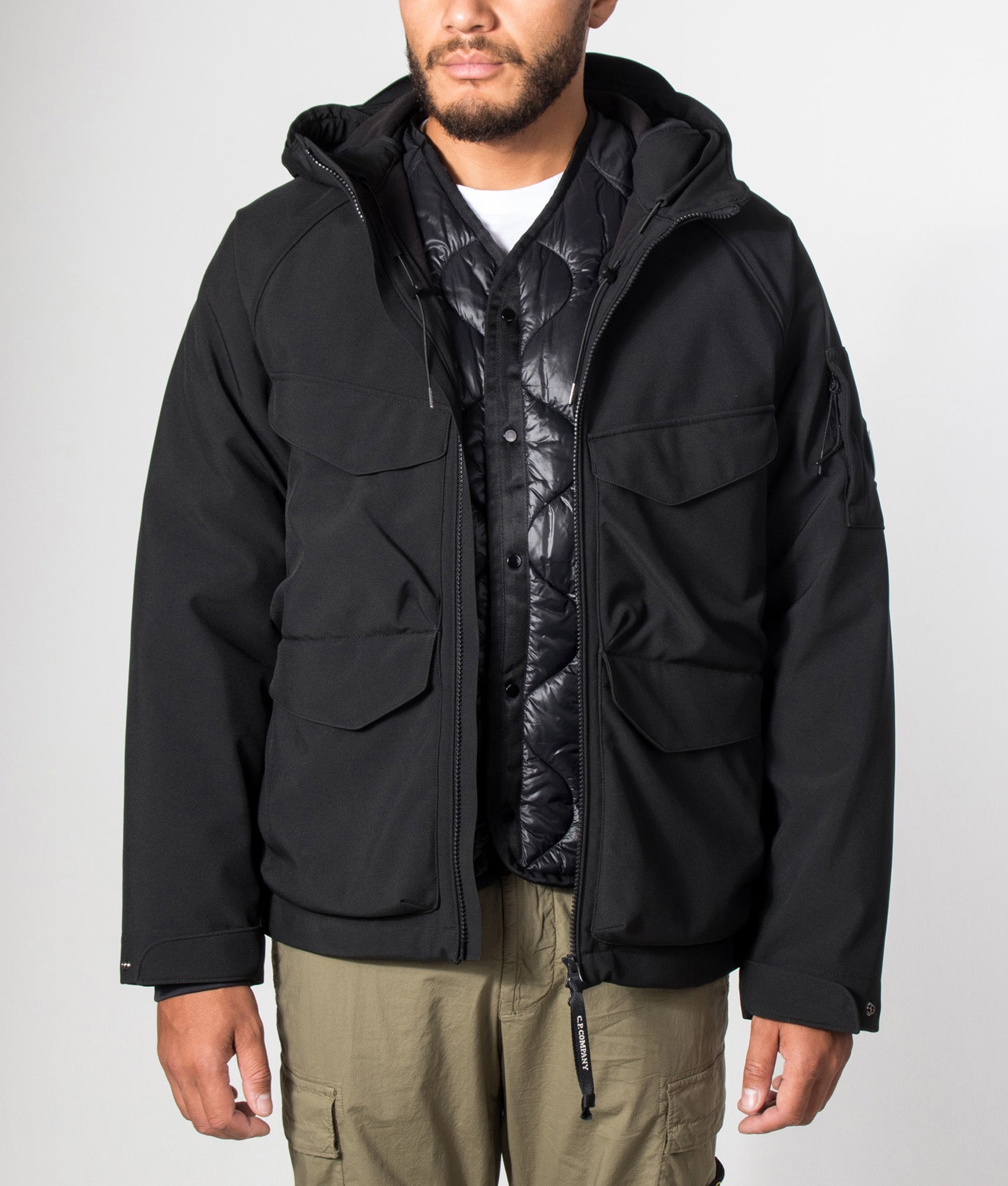 C.P. Company C.P. Shell-R Padded Hooded Lens Jacket in Black at EQVVS Menswear. Model front shot.
