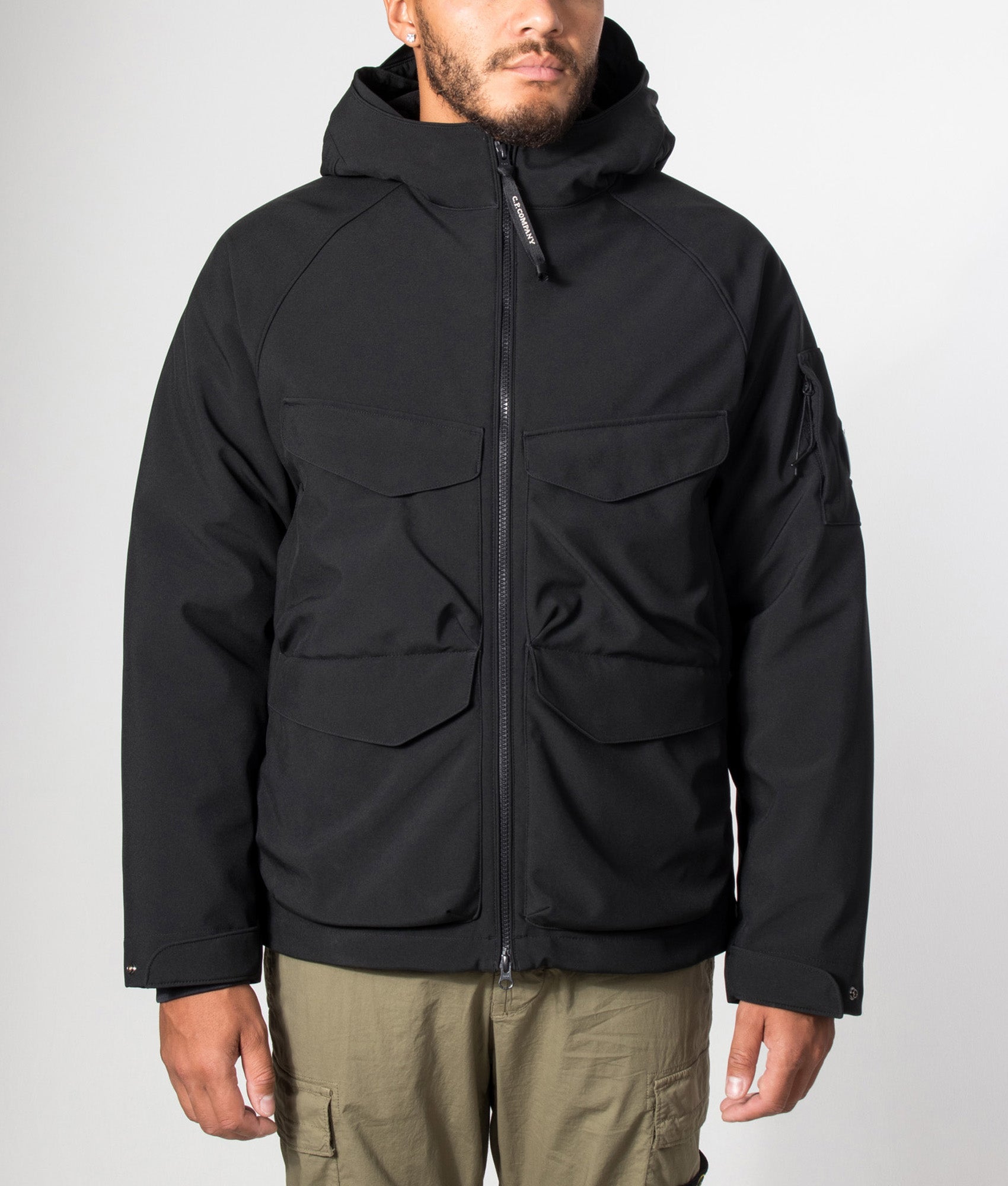 C.P. Company C.P. Shell-R Padded Hooded Lens Jacket in Black at EQVVS Menswear. Model front shot.
