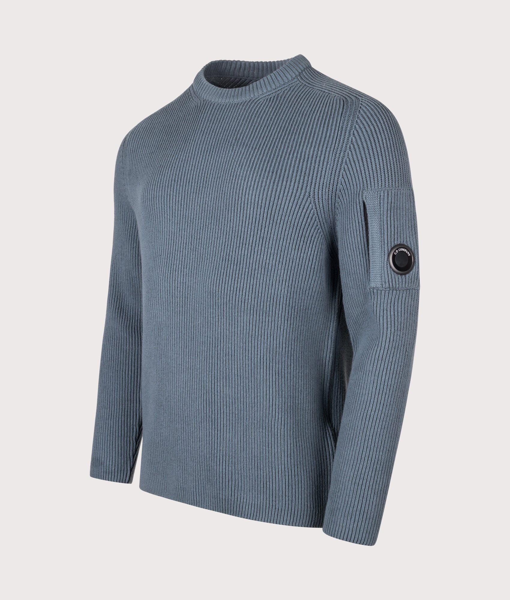 C.P. Company Full Rib Cotton Crewneck Lens Jumper in Orion Blue at EQVVS Menswear. Angled front shot.