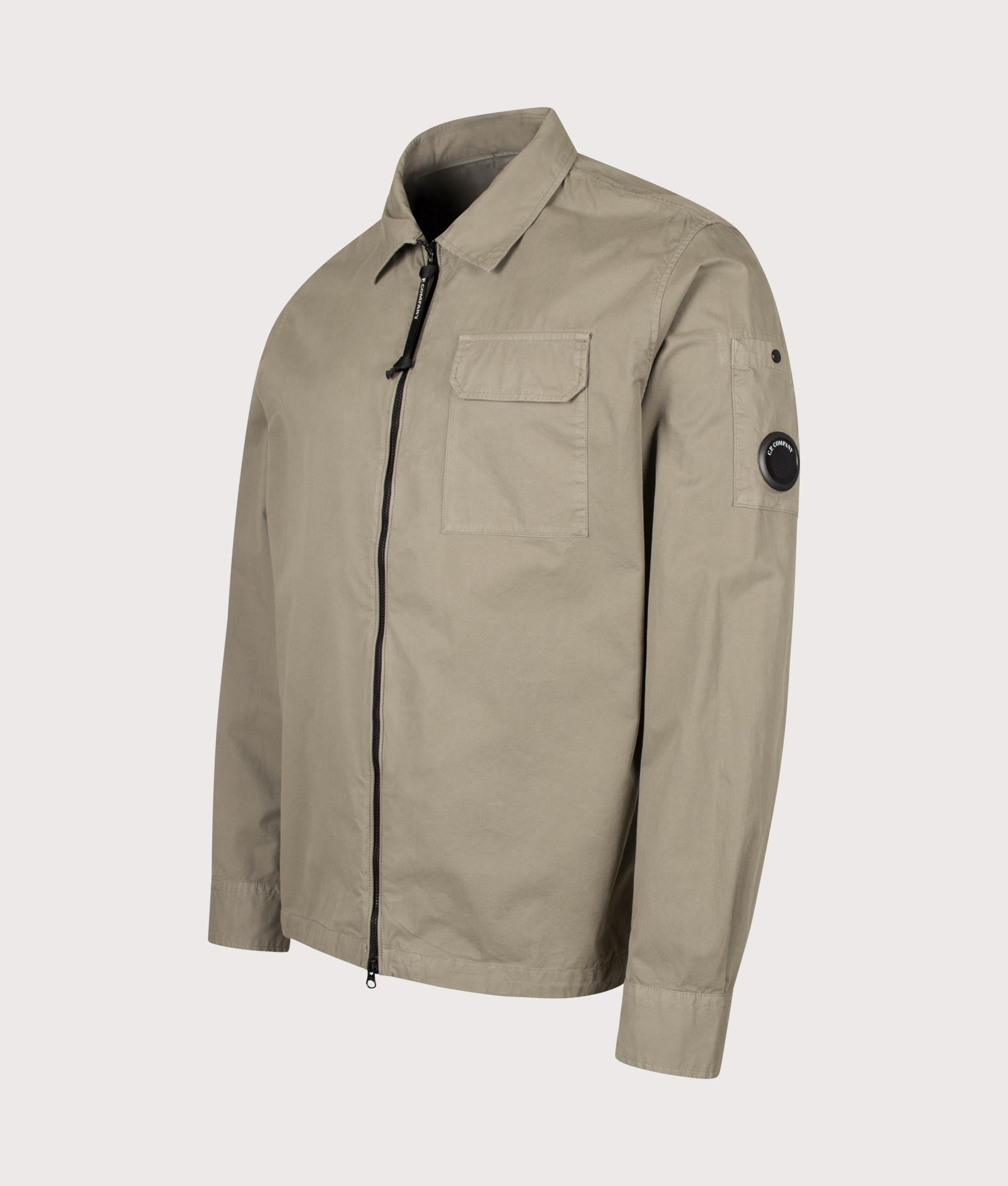C.P. Company Organic Gabardine Zipped Lens Overshirt in Fallen Rock at EQVVS Menswear. Angled front shot.