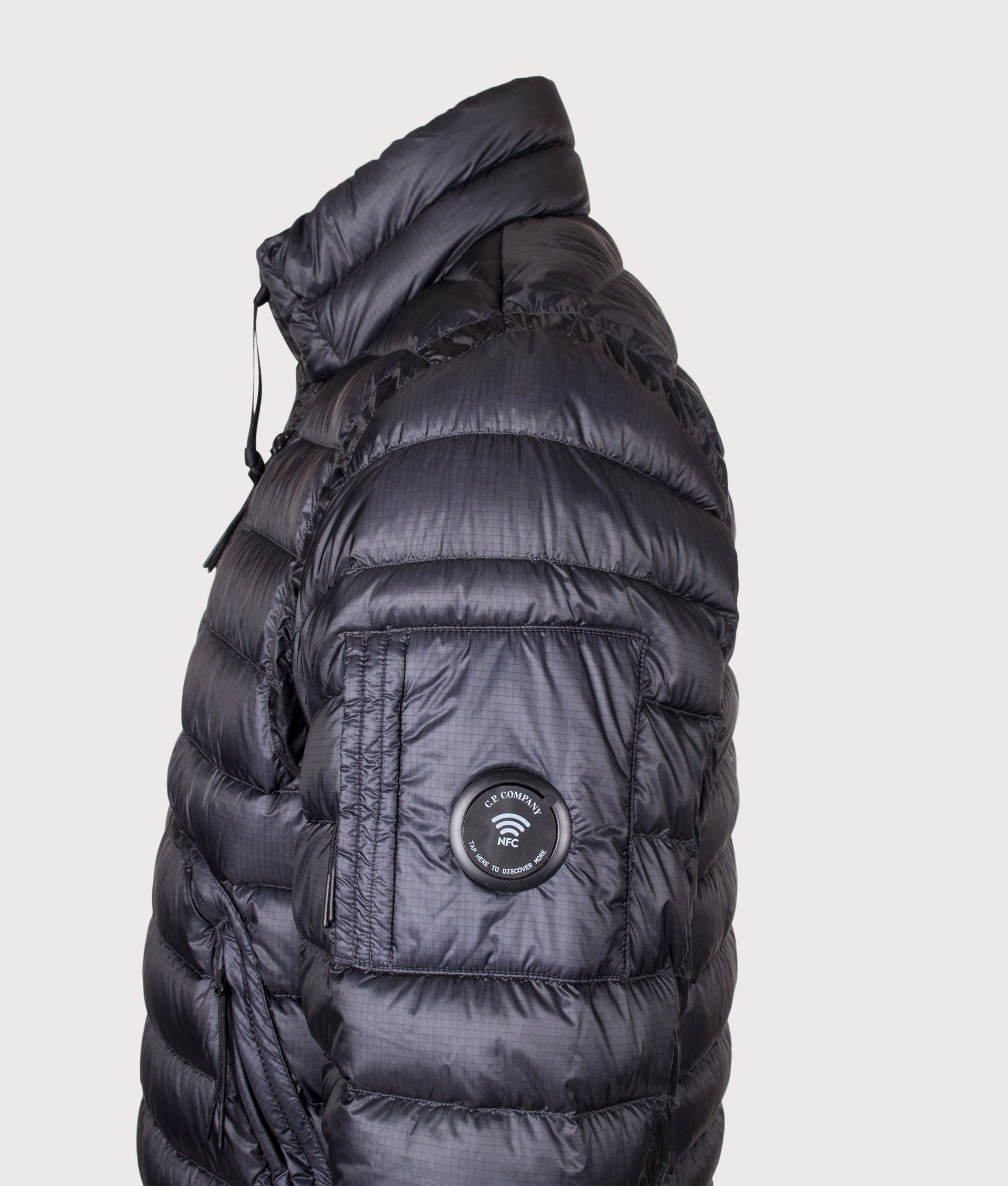 C.P. Company D.D. Shell Lens Down Jacket in Black at EQVVS Menswear. NFC detail shot.