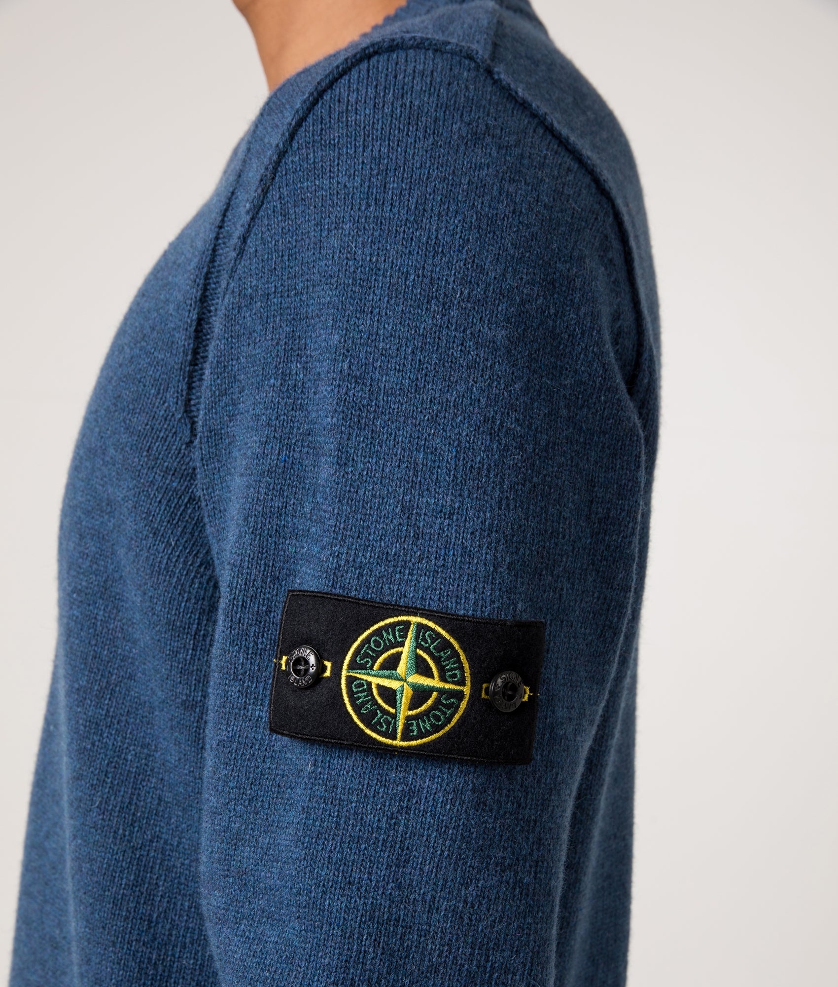 Stone Island Lambswool Crew Neck Jumper in Steel Blue at EQVVS Menswear. Side detail shot.