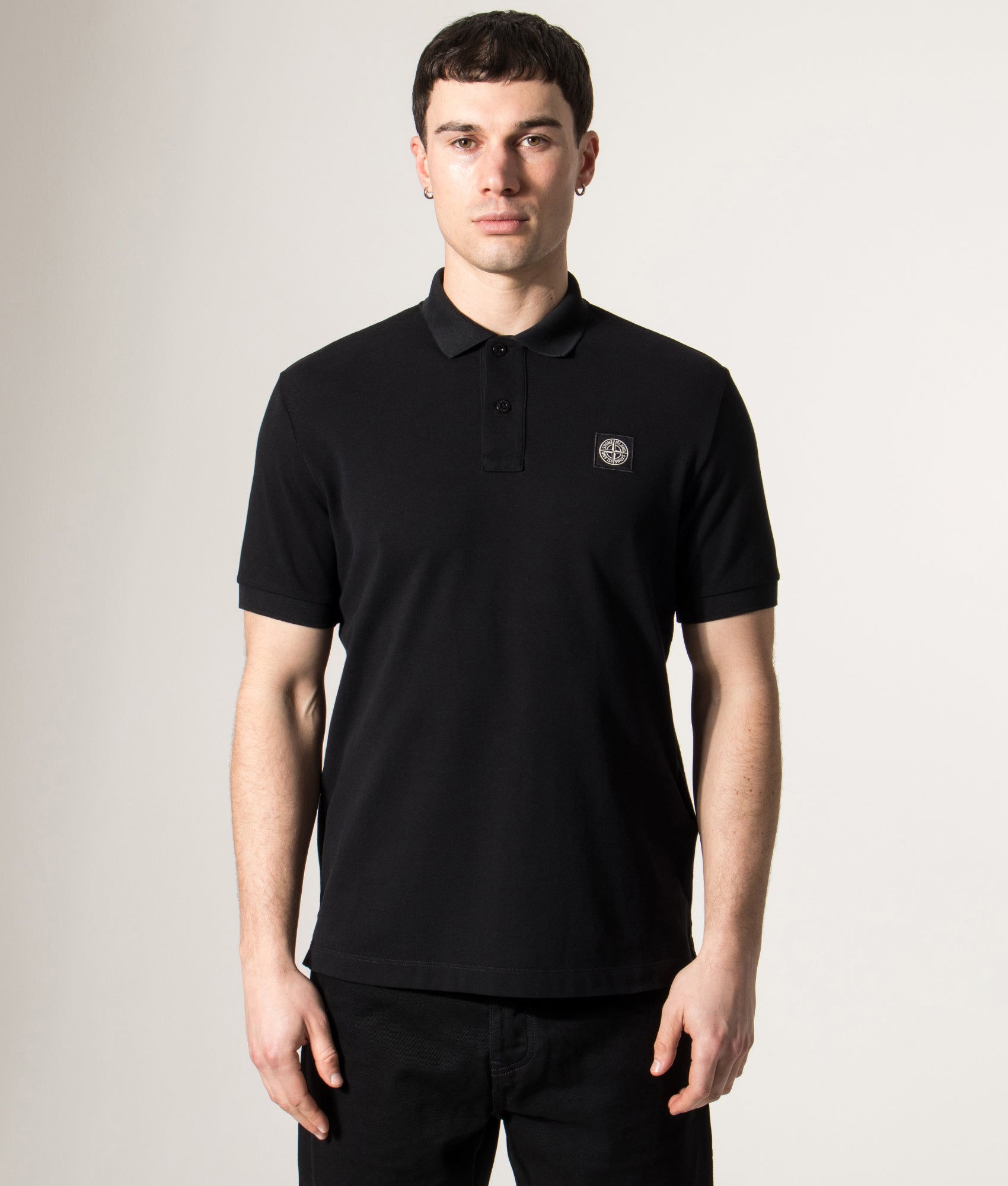Stone Island Slim Fit Compass Patch Polo Shirt in Black at EQVVS Menswear. Model front shot.