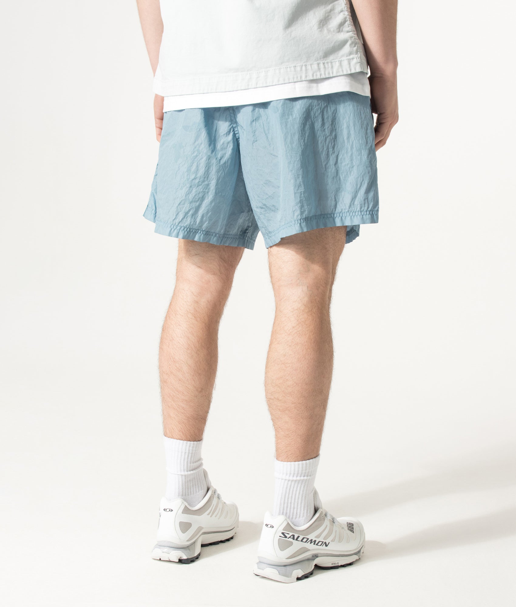 Stone Island Relaxed Fit Water Reactive Faded Camo Swim Shorts in Powder Blue at EQVVS Menswear. Angled model back shot.
